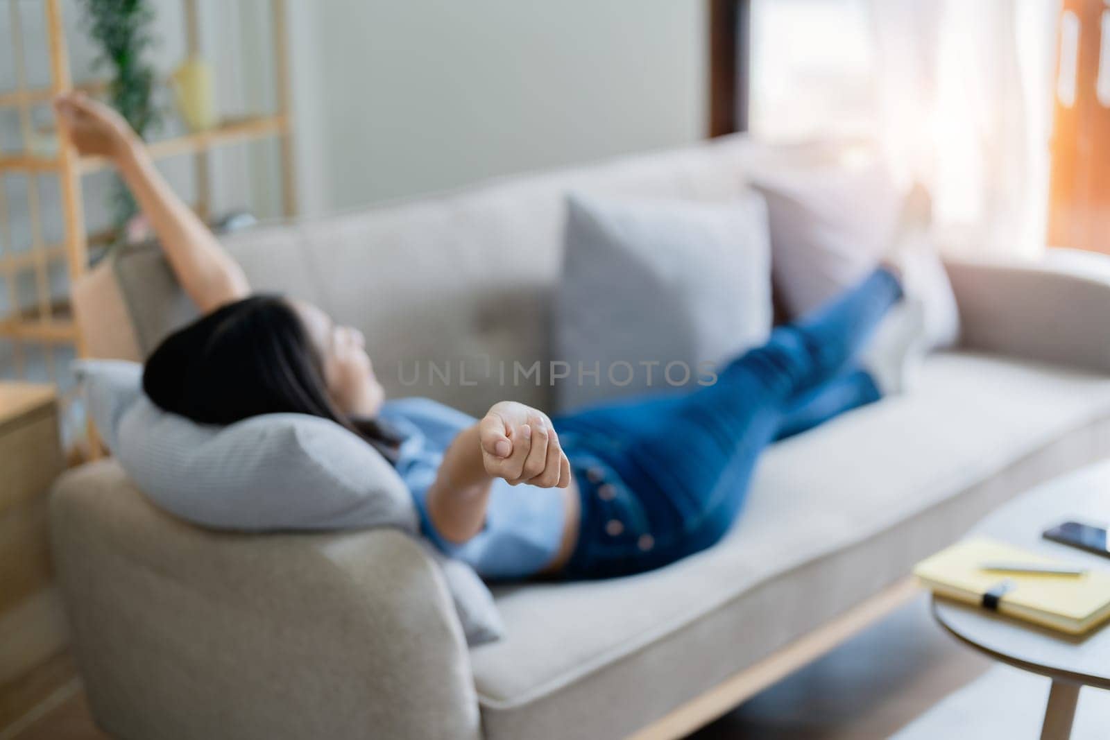 Home lifestyle woman relaxing sleeping on sofa patio living room. Happy lady lying down on comfortable pillows taking a nap for wellness and health. Tropical vacation