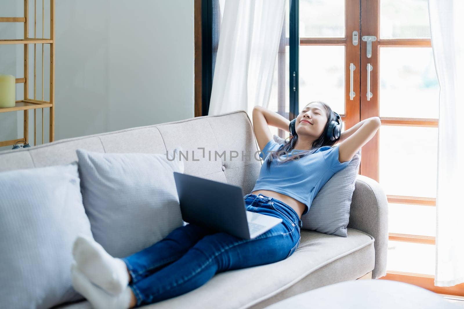 Home lifestyle woman relaxing sleeping on sofa patio living room. Happy lady lying down on comfortable pillows taking a nap for wellness and health. Tropical vacation