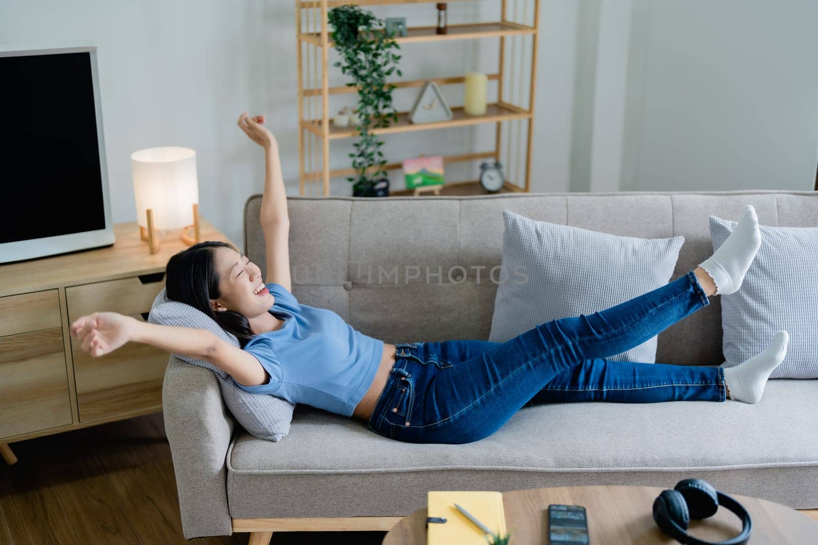 Home lifestyle woman relaxing sleeping on sofa patio living room. Happy lady lying down on comfortable pillows taking a nap for wellness and health. Tropical vacation