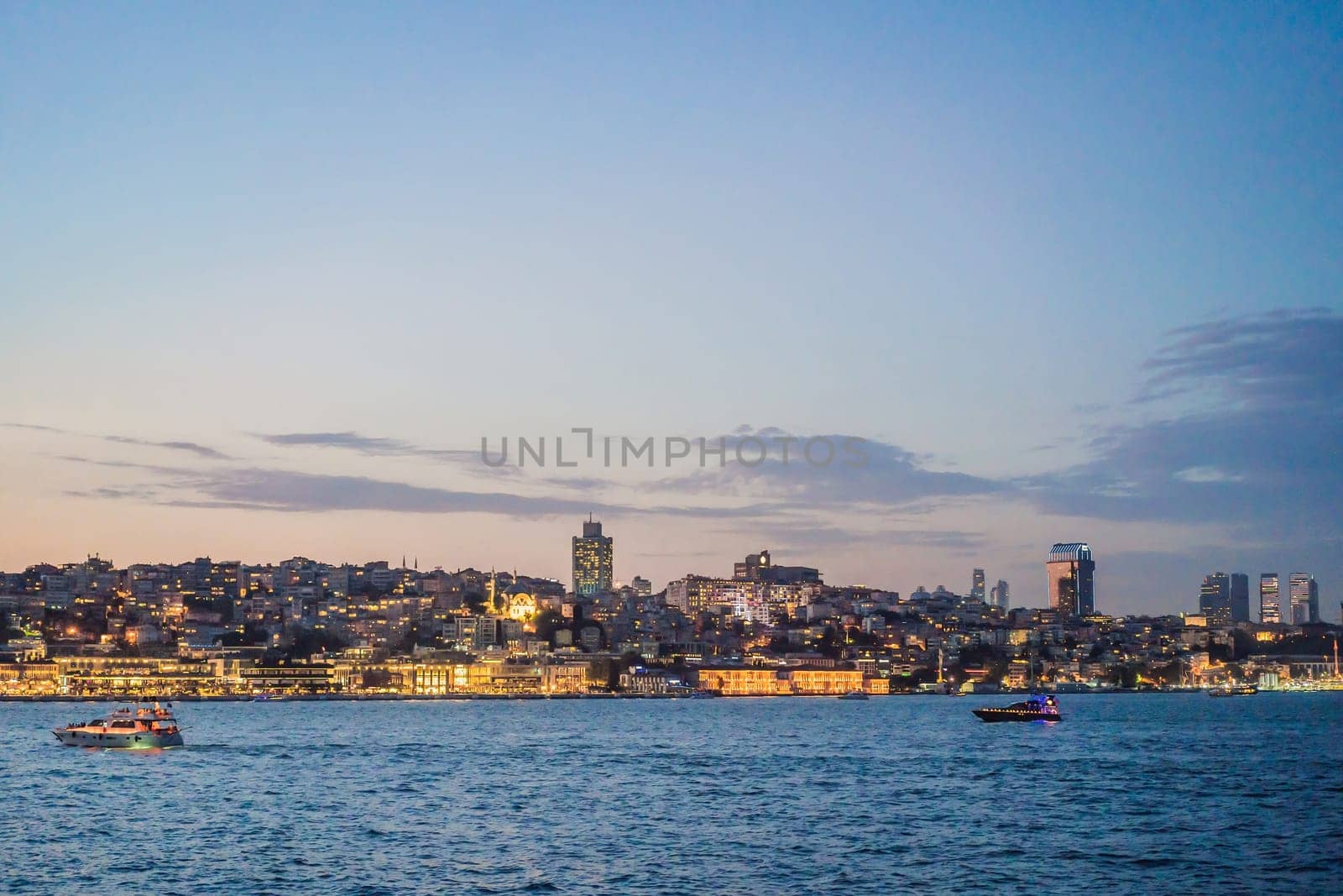 Istanbul at sunset, Turkey. Tourist boat sails on Golden Horn in summer. Beautiful sunny view of Istanbul waterfront with old mosque. Concept of travel, tourism and vacation in Istanbul and Turkey. Turkiye.