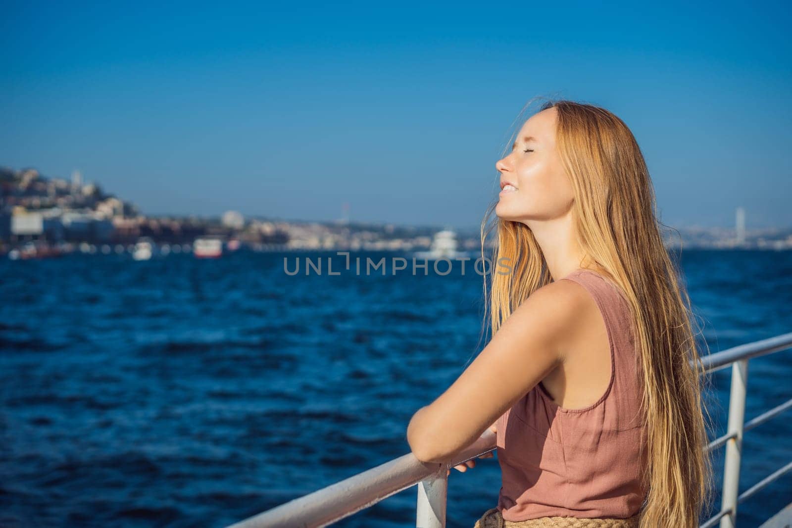 Happy woman enjoying the sea from ferry boat crossing Bosphorus in Istanbul. Summer trip to Istanbul.