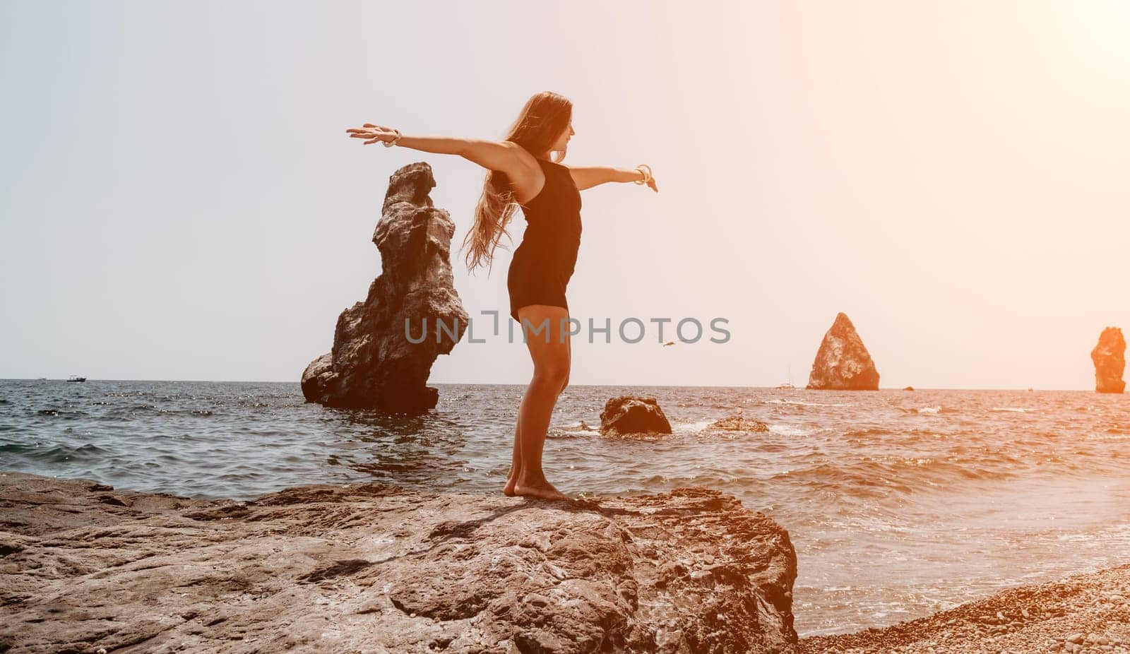 Woman travel sea. Young Happy woman in a long red dress posing on a beach near the sea on background of volcanic rocks, like in Iceland, sharing travel adventure journey