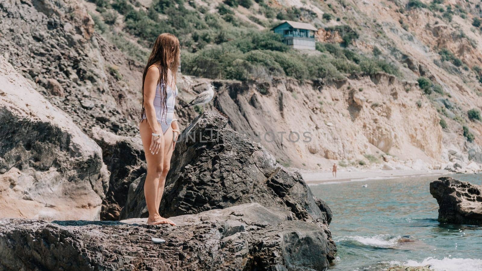 Woman travel sea. Happy tourist in white bikini enjoy taking picture outdoors for memories. Woman traveler posing on the beach at sea surrounded by volcanic mountains, sharing travel adventure journey by panophotograph