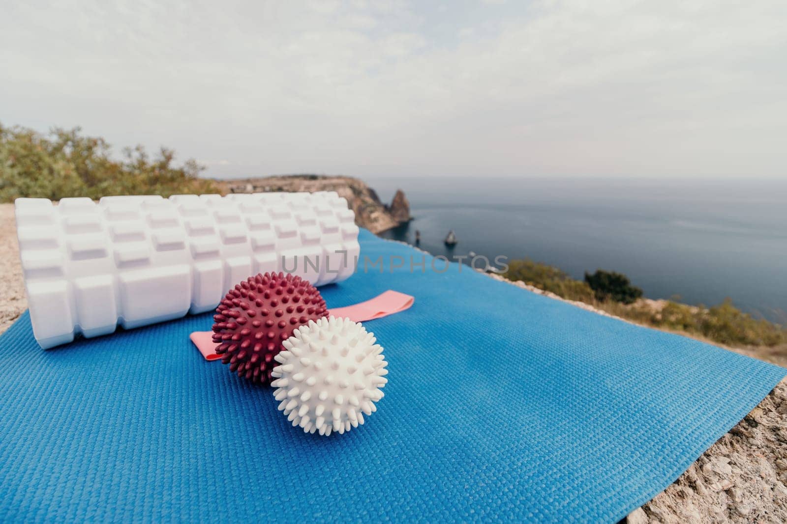 Middle aged well looking woman with black hair doing Pilates with the ring on the yoga mat near the sea on the pebble beach. Female fitness yoga concept. Healthy lifestyle, harmony and meditation.