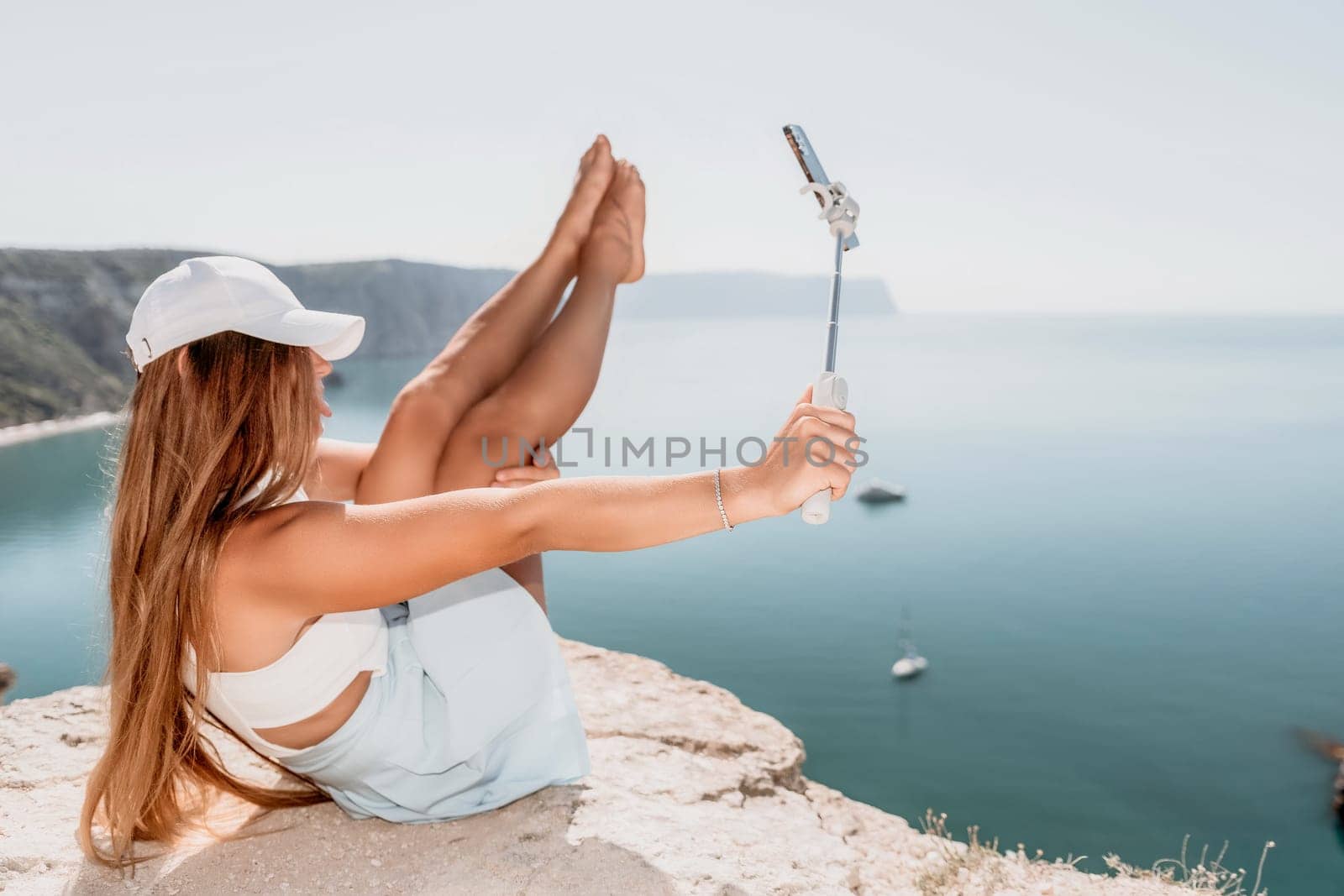 Digital nomad, Business woman working on laptop by the sea. Pretty lady typing on computer by the sea at sunset, makes a business transaction online from a distance. Freelance, remote work on vacation by panophotograph