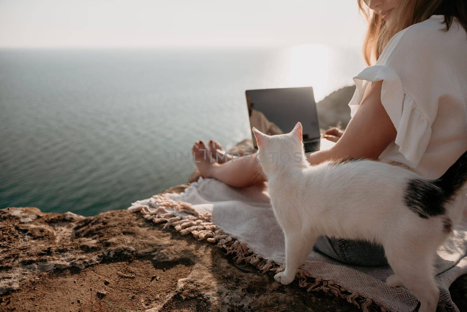 Woman sea laptop. Business woman in yellow hat working on laptop by sea. Close up on hands of pretty lady typing on computer outdoors summer day. Freelance, digital nomad, travel and holidays concept.