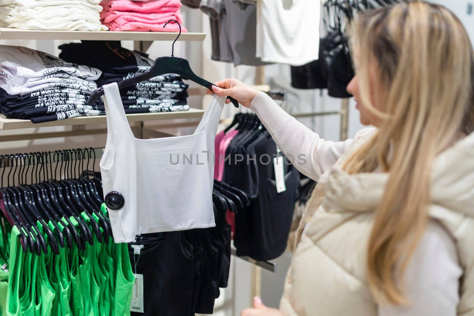 Happy young woman buying new clothes in store. Sale shopping fashion and people concept.