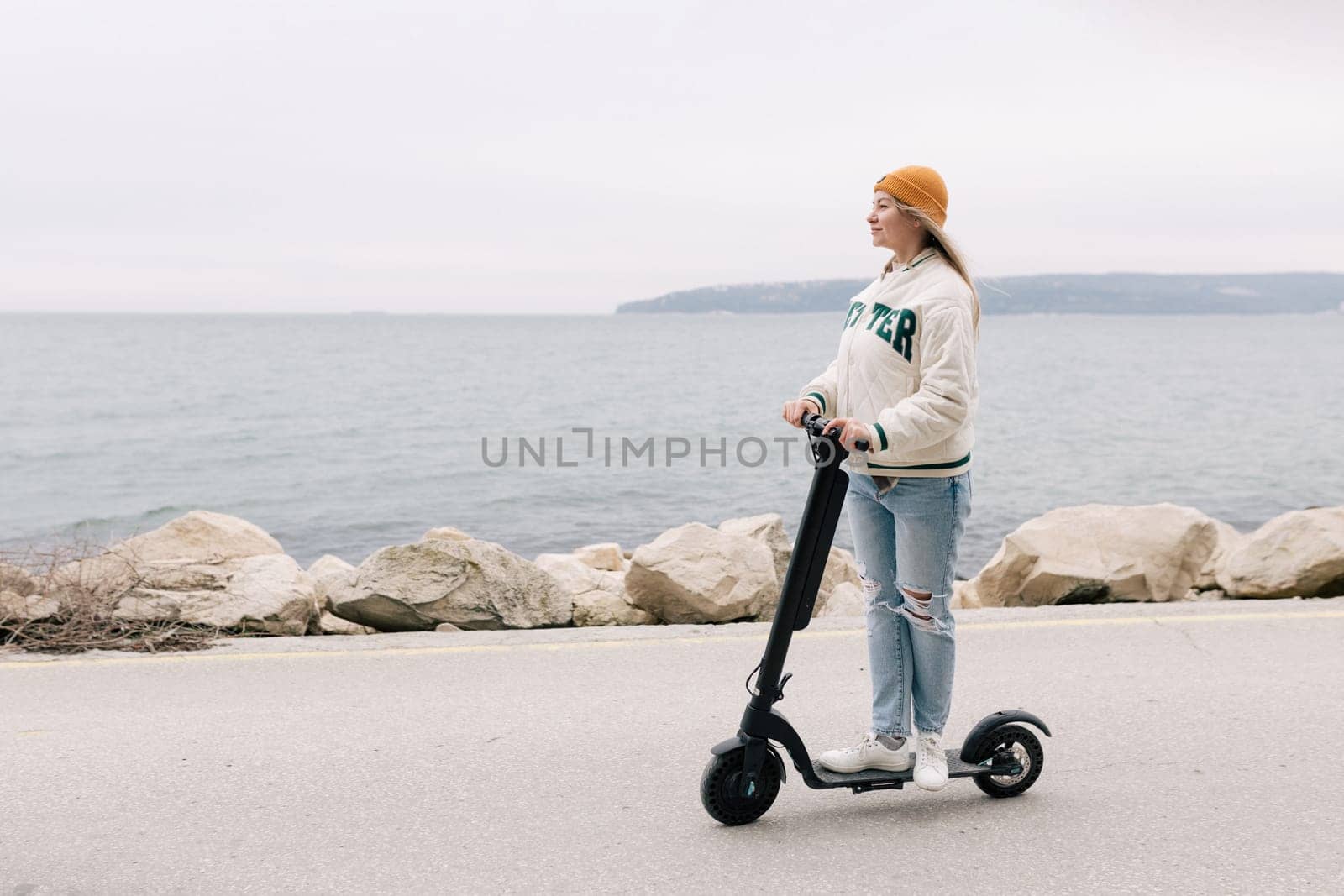 Milan, Italy - February 21, 2018: Attractive girl riding an electric scooter along the promenade in Europe.