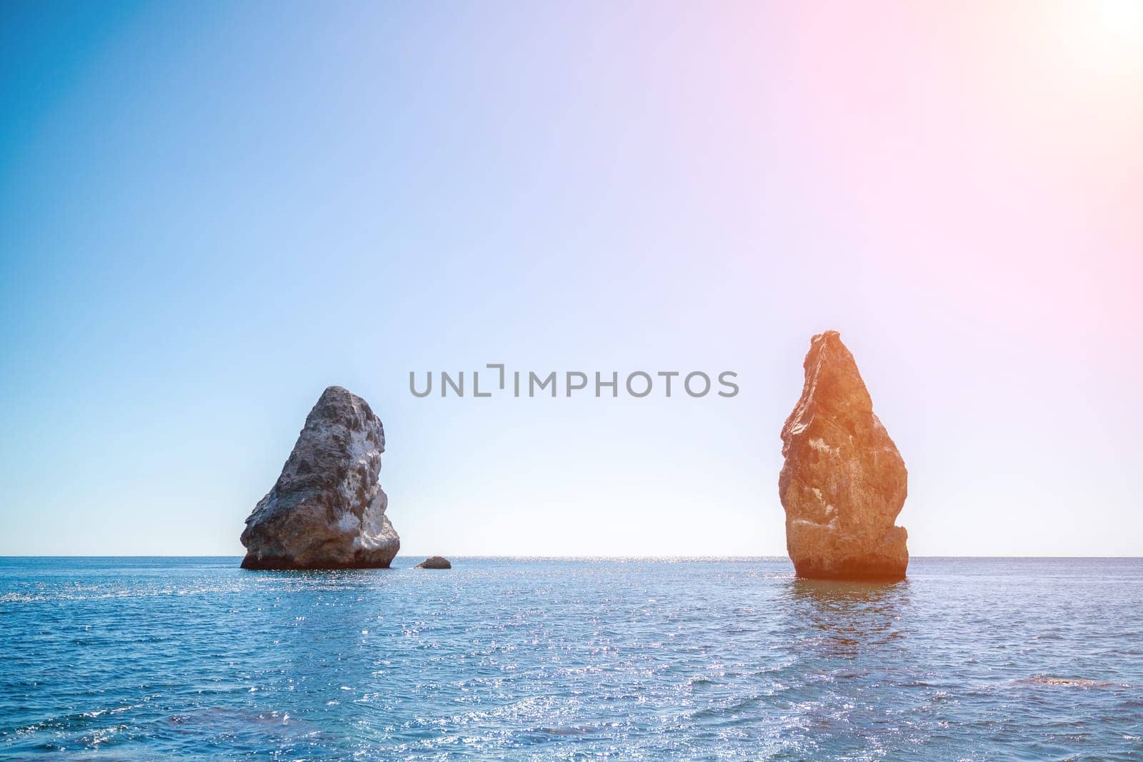 Two rocks stick out of the water in the middle of the turquoise sea. Scenic ocean views. High quality photo. Like in Iceland.