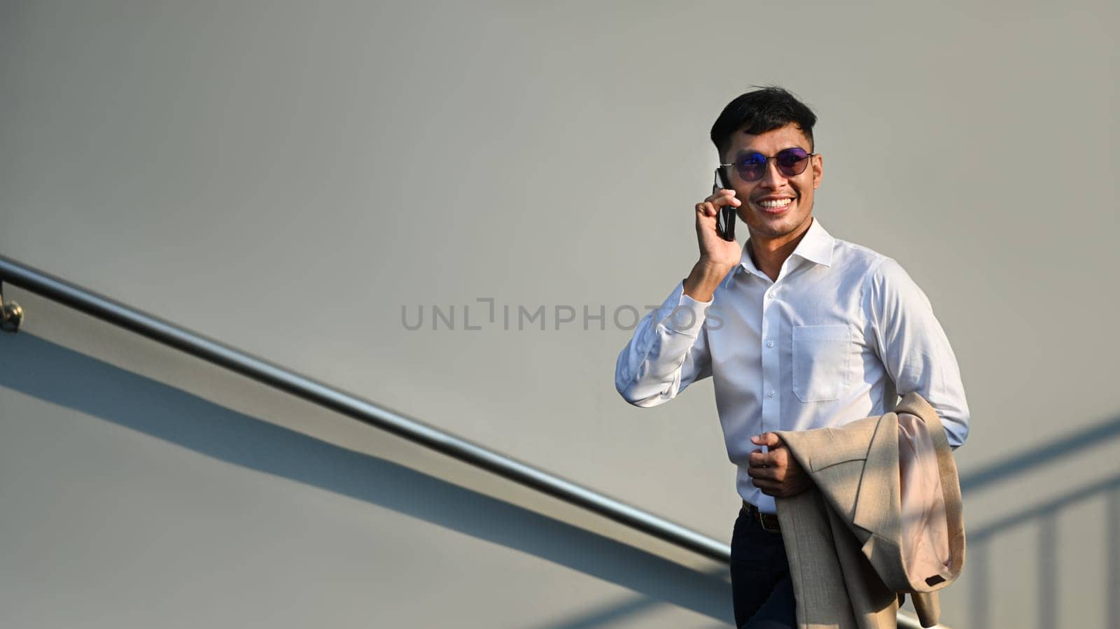 Shot of millennial businessman talking on mobile phone and walking up the stairs, hurrying to work in the morning.