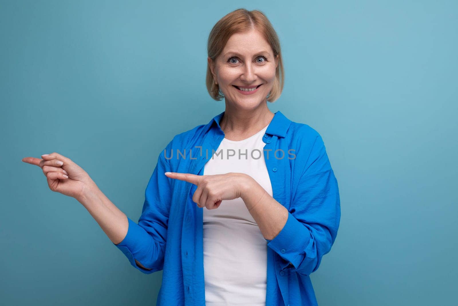 smiling genius blond middle aged woman on blue background with copyspace.