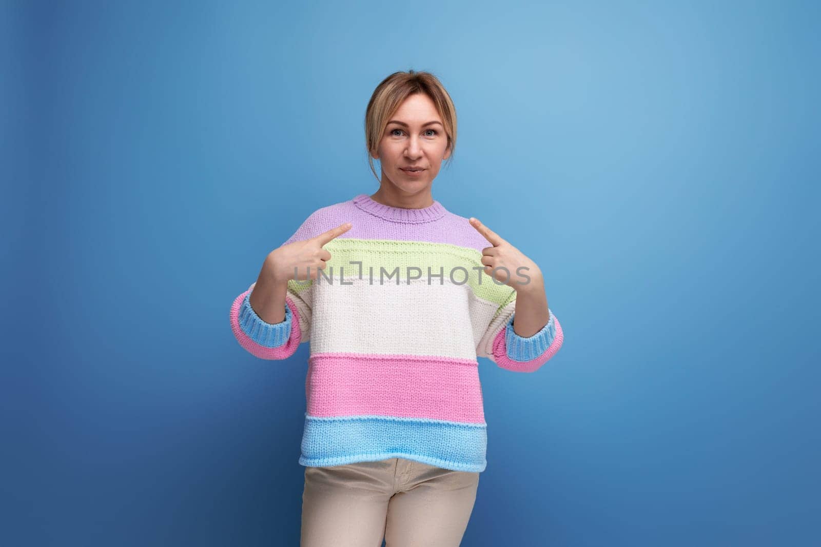 blond girl shows her hands at herself on a blue background.