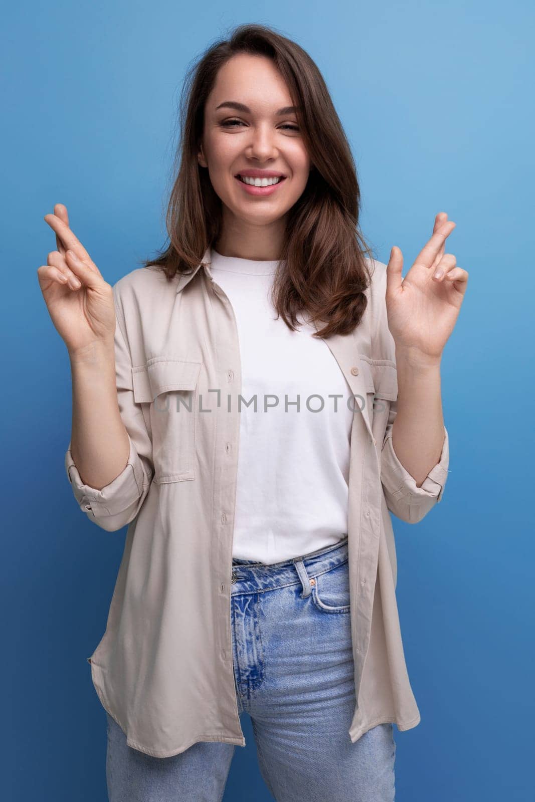 pretty european young brunette woman in shirt and jeans on blue background.