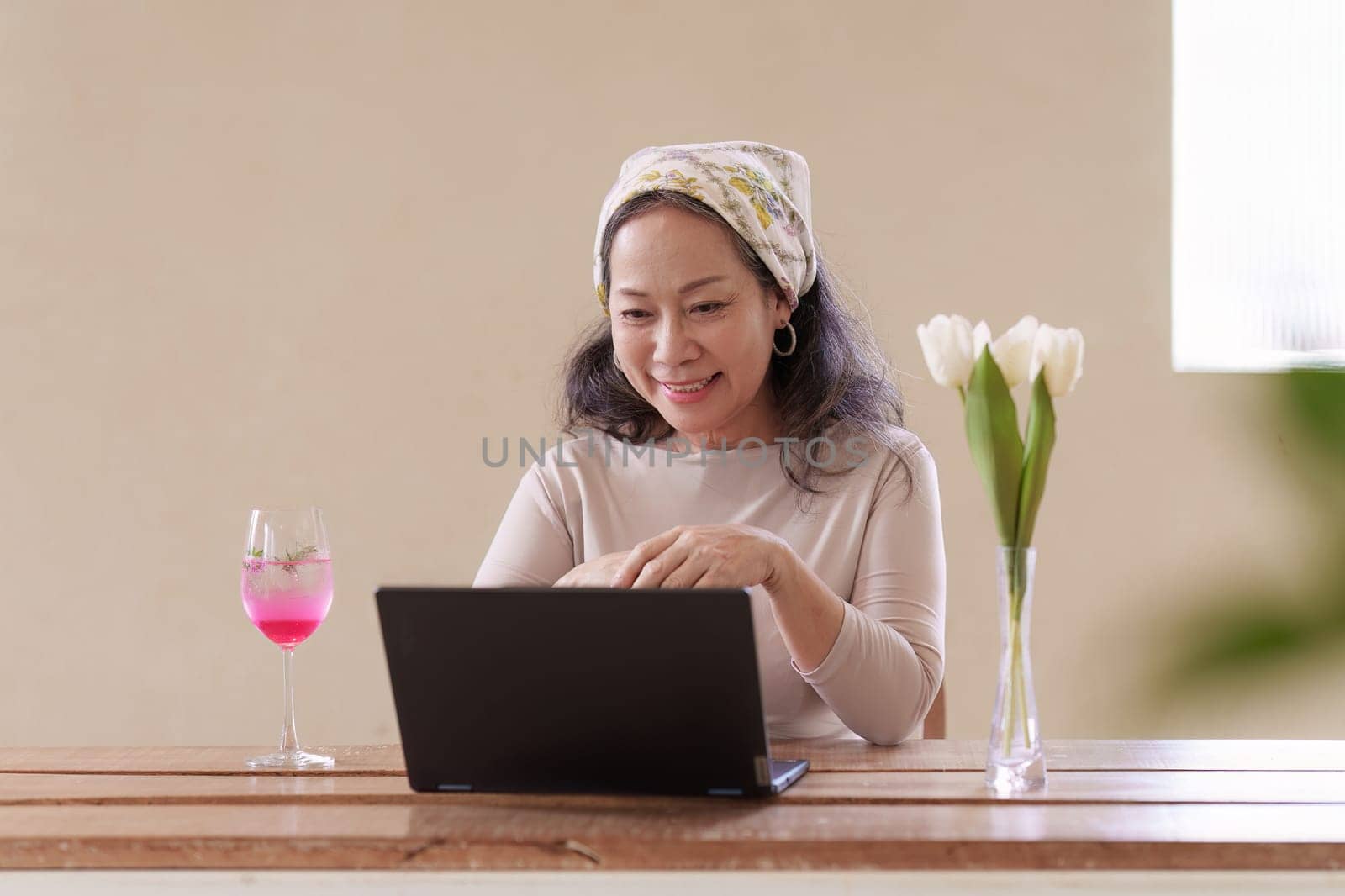 Old woman in summer theme work at cafe using laptop computer. work and travel concept.