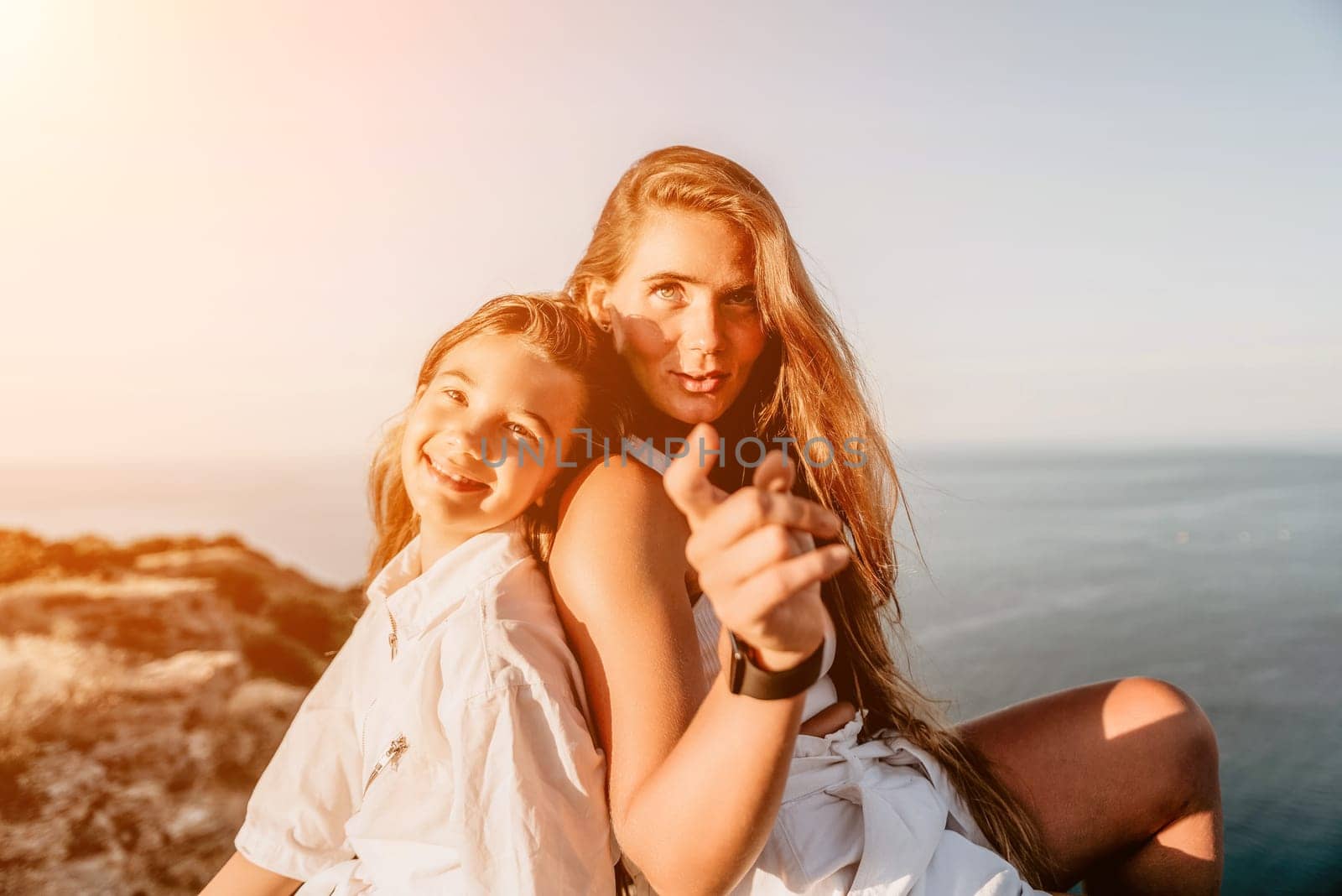 Close up portrait of mom and her teenage daughter hugging and smiling together over sunset sea view. Beautiful woman relaxing with her child.