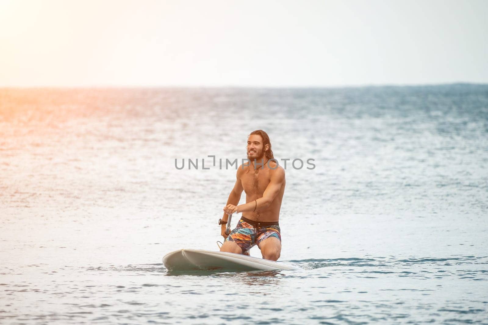 Sea woman and man on sup. Silhouette of happy young woman and man, surfing on SUP board, confident paddling through water surface. Idyllic sunset. Active lifestyle at sea or river