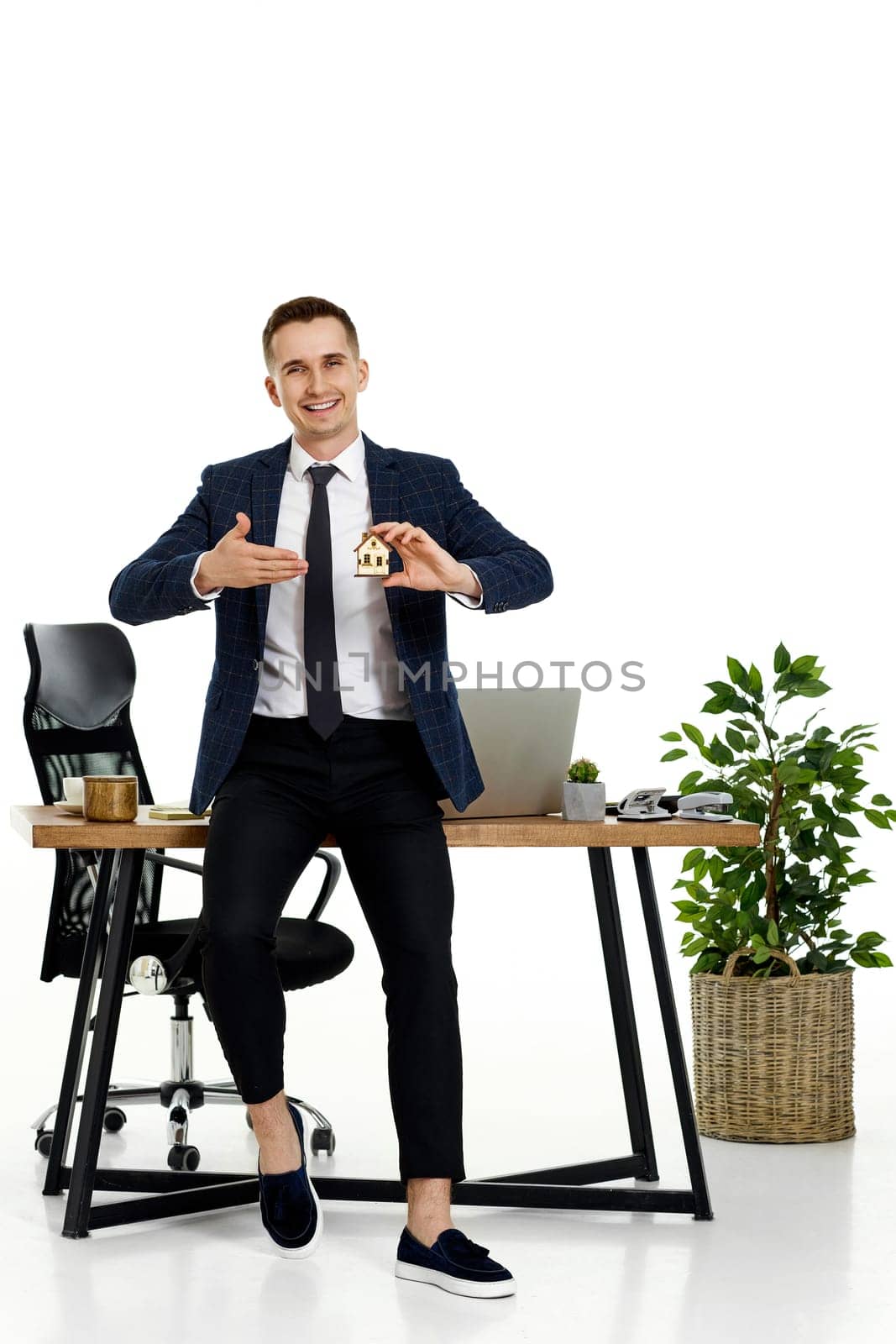 Successful caucasian businessman holding toy house in the office. real estate insurance
