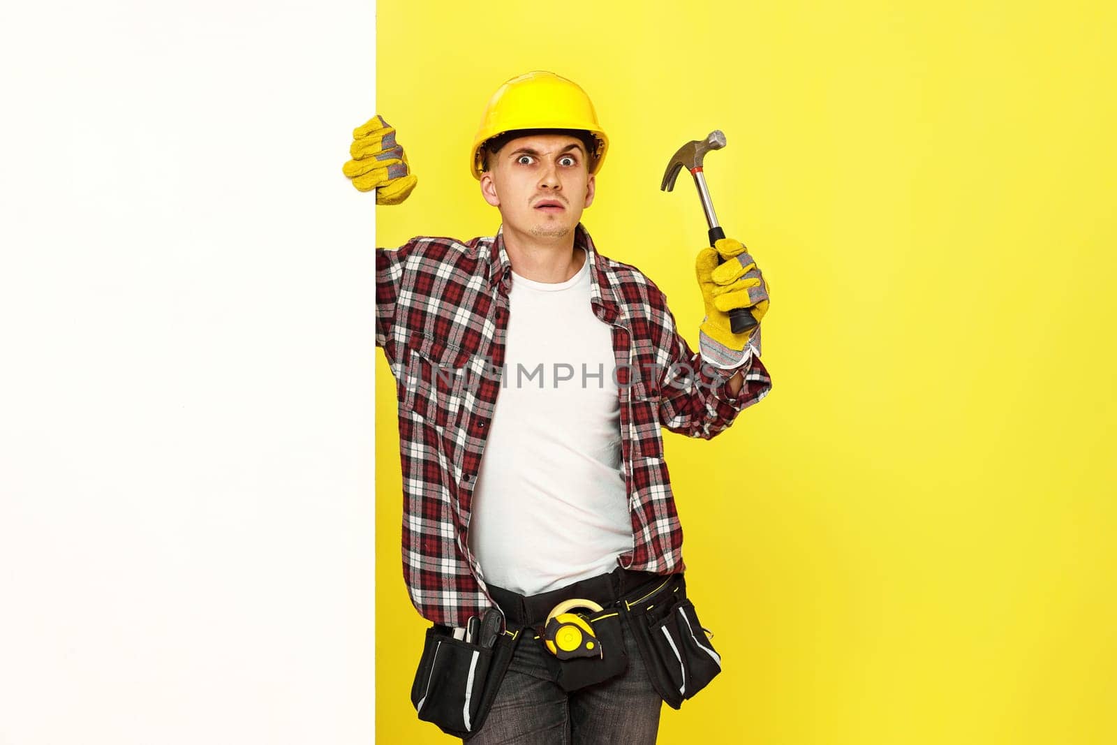 professional builder in work clothes in helmet holding hammer. copy space for text