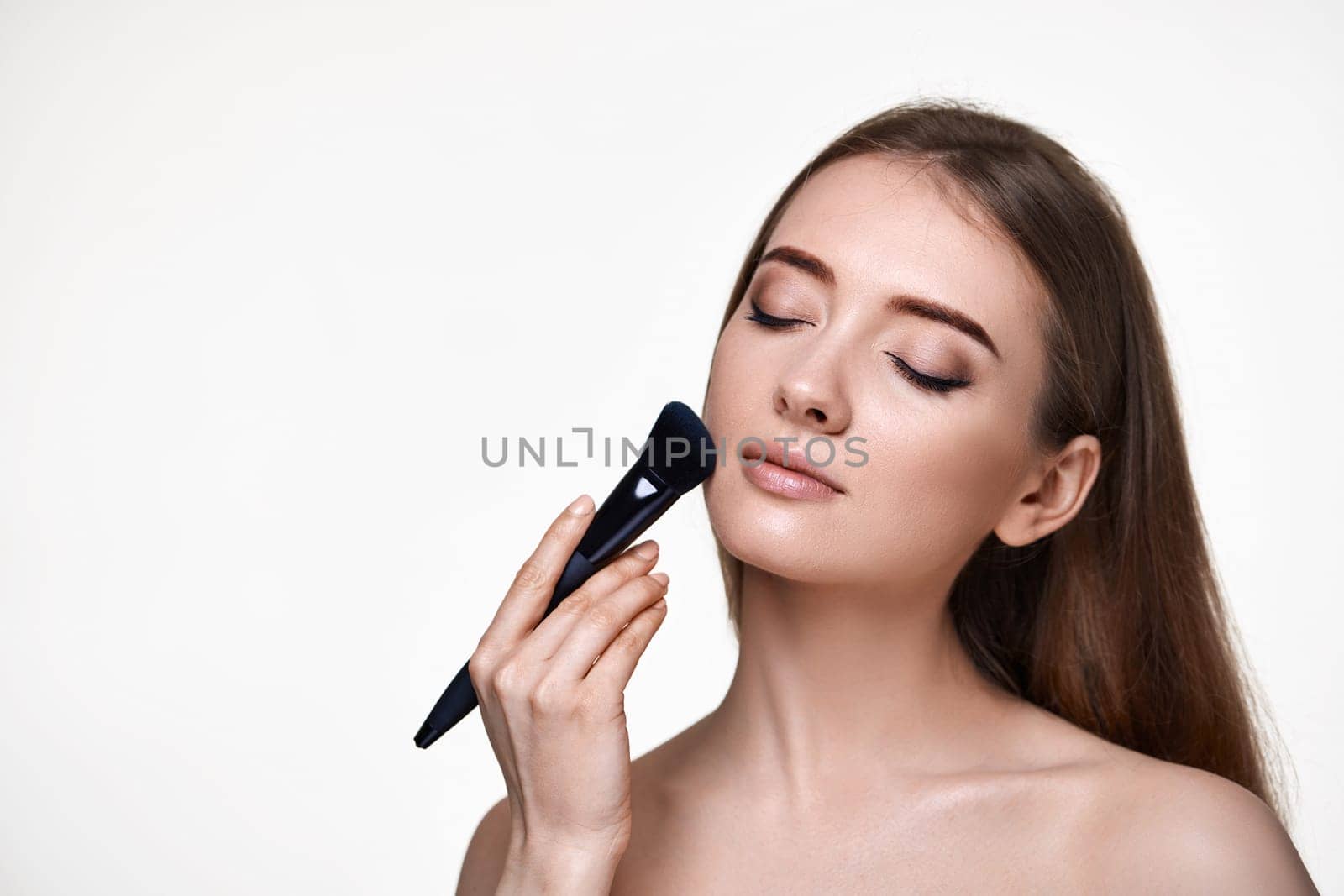 beautiful woman posing with make-up brush for powder isolated on white background. copy space