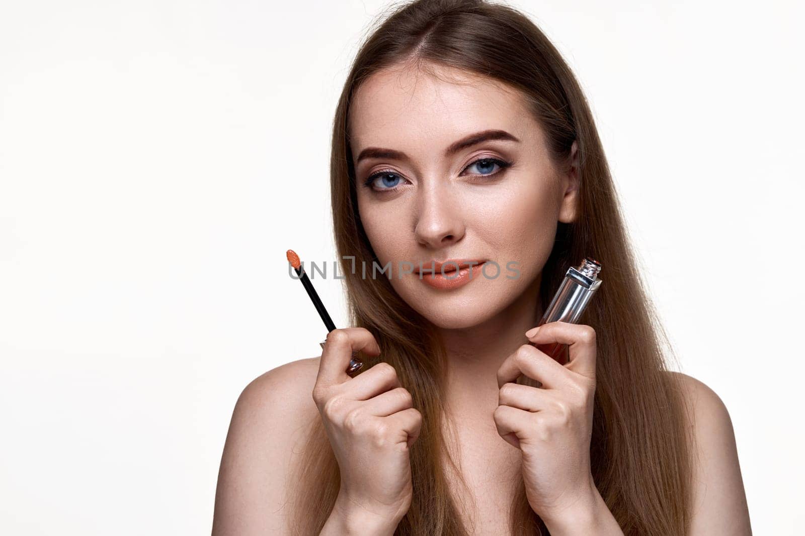 pretty young woman testing nude lip gloss isolated on white background