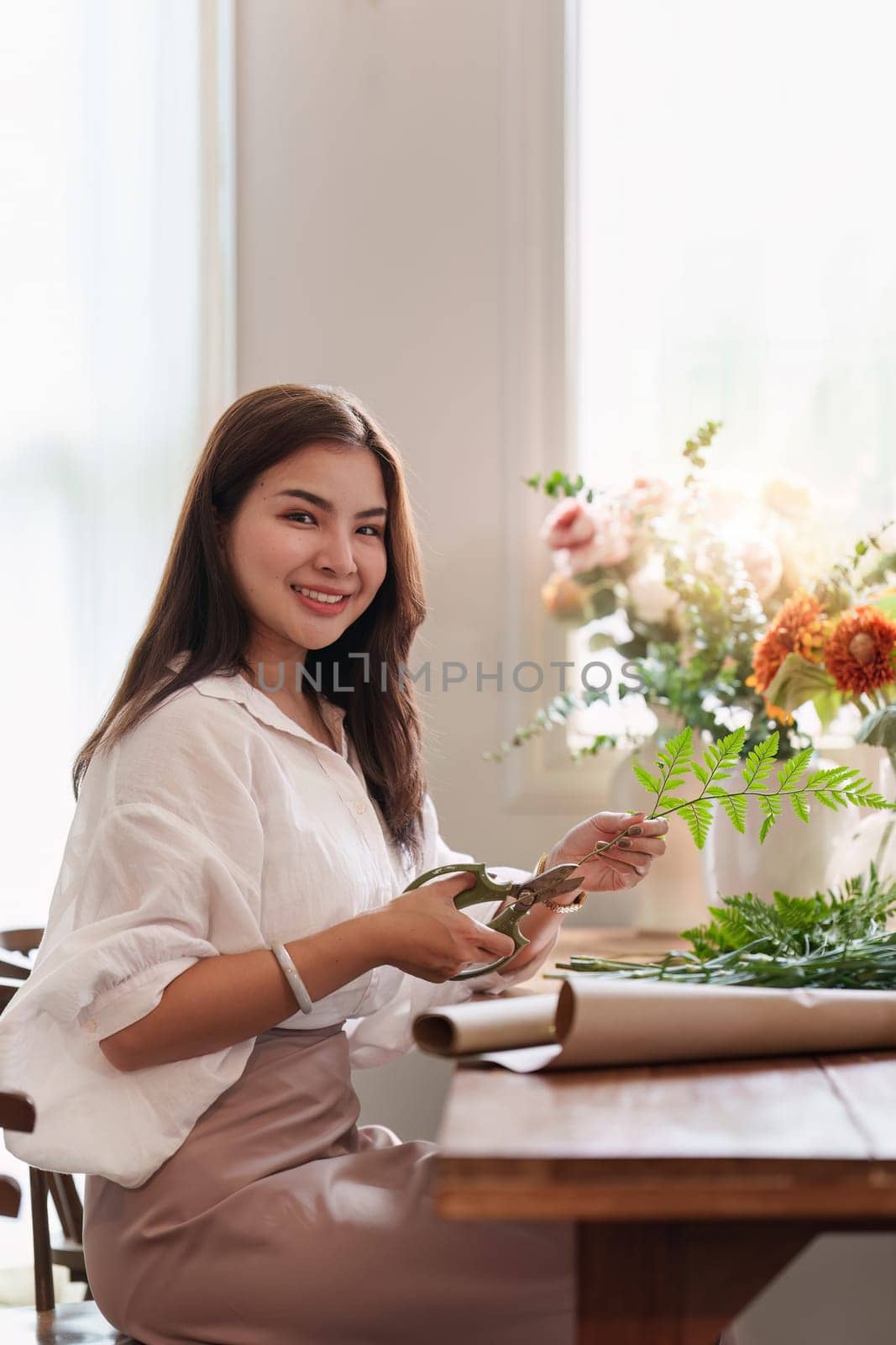 Startup, small business, flower shop. Young pretty florist putting a flower on a vase.