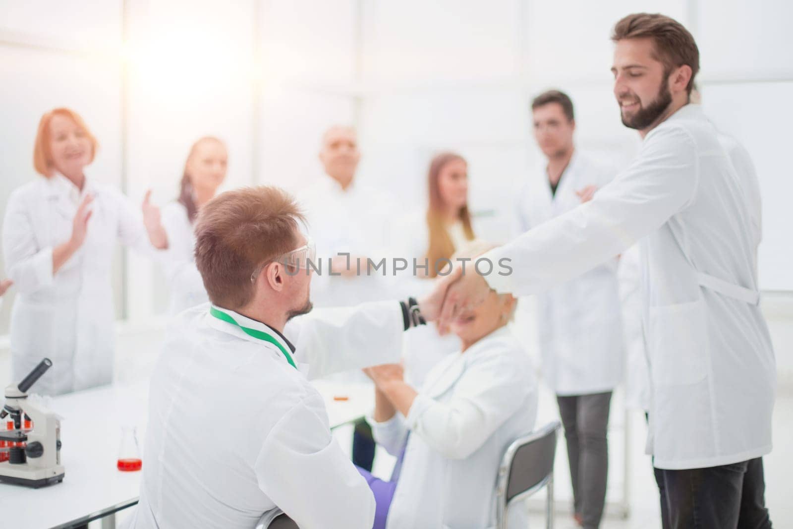 group of scientists congratulating their colleague in the workplace . success concept