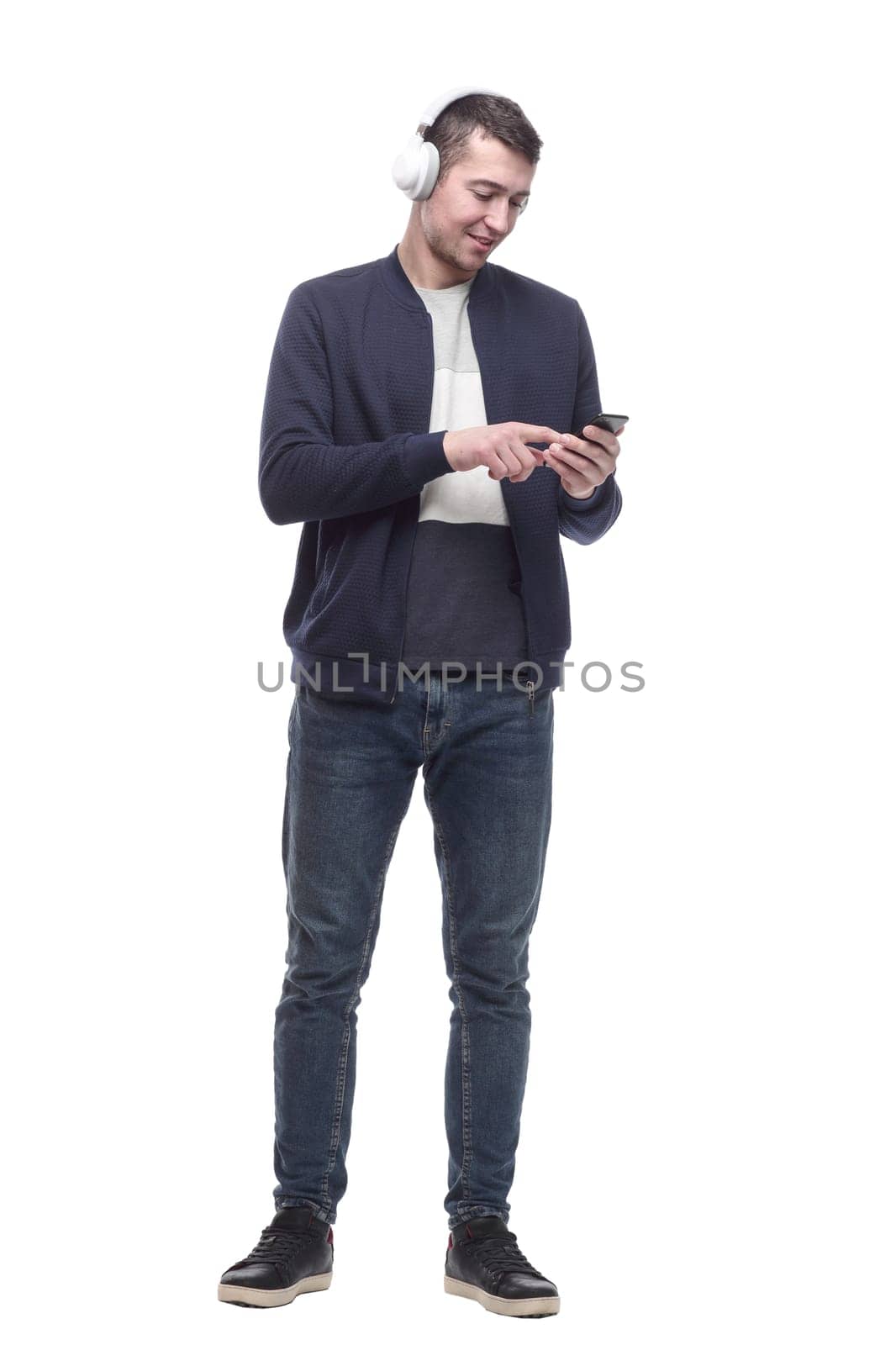 young man with a smartphone listening to music through headphones. isolated on a white