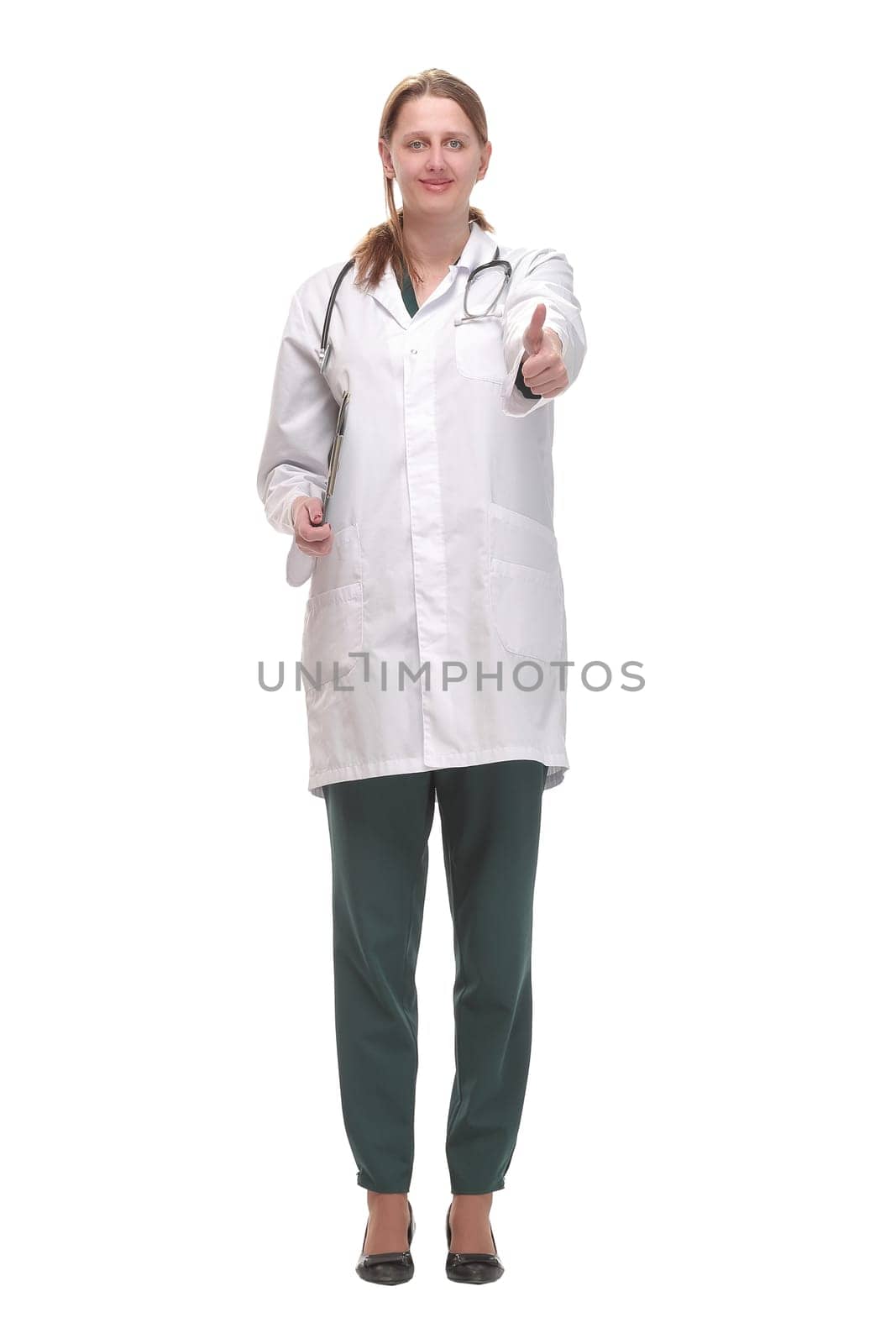Attractive female doctor standing on white background holding clipboard and doing paperwork, looking up at camera.