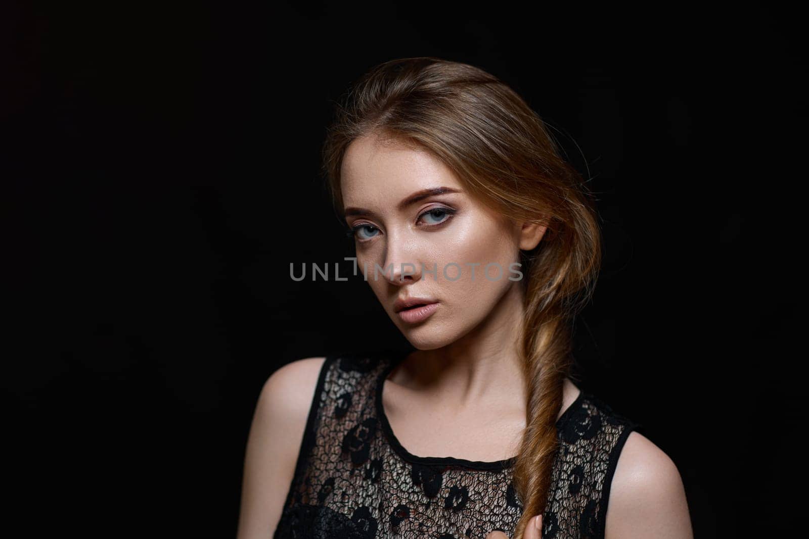 gorgeous brunette woman with long hair in black dress on black background. copy space