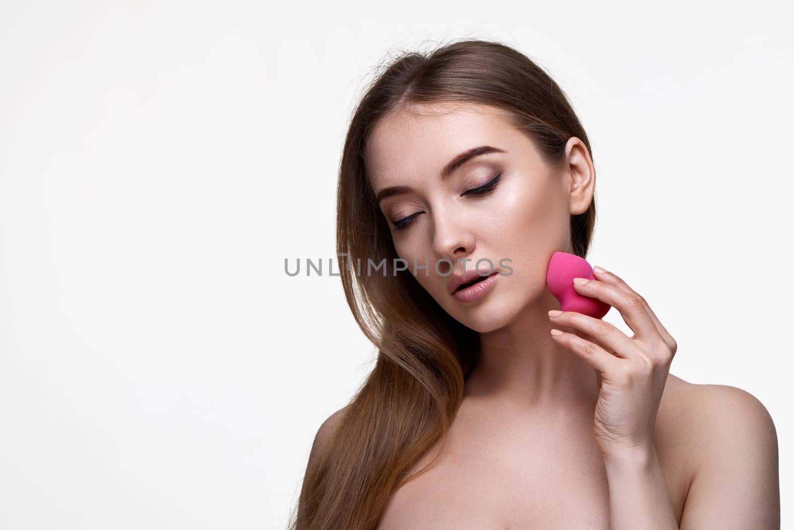 attractive young woman using pink cosmetic sponges isolated on white background. copy space