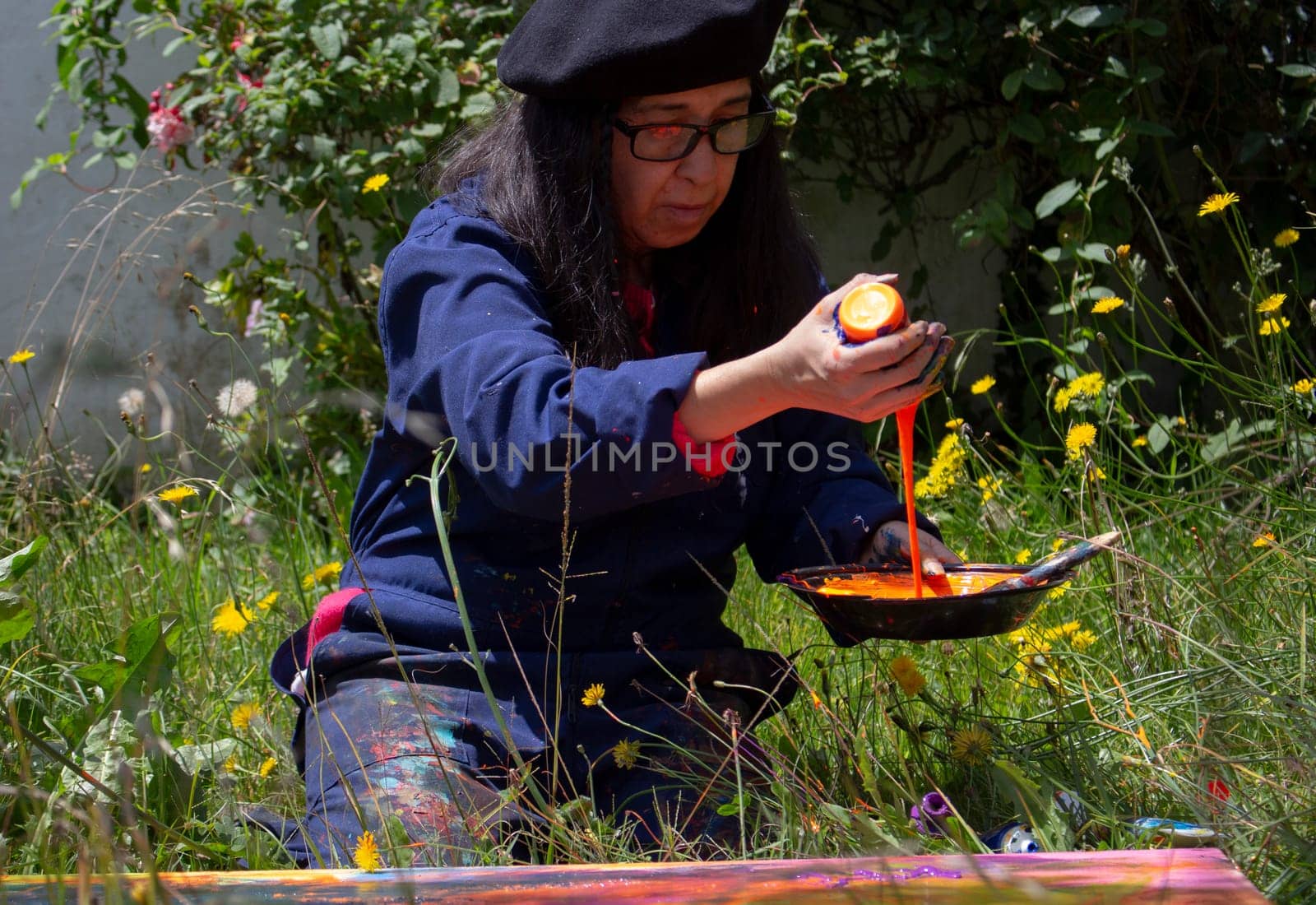 retired woman concentrating on mixing colors to paint an abstract picture in her garden. High quality photo