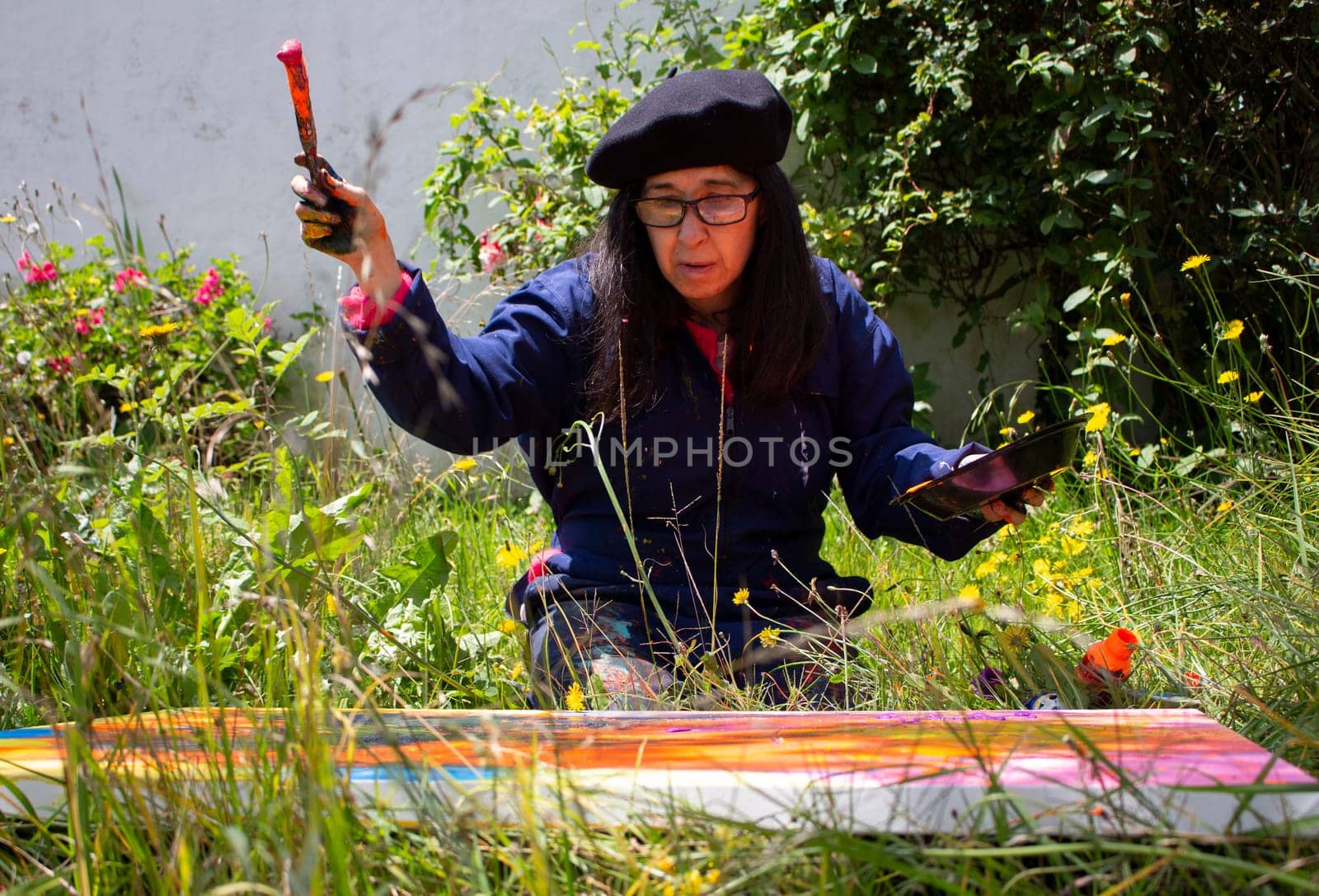 retired woman painting an abstract picture at the creative peak in a garden surrounded by plants. High quality photo