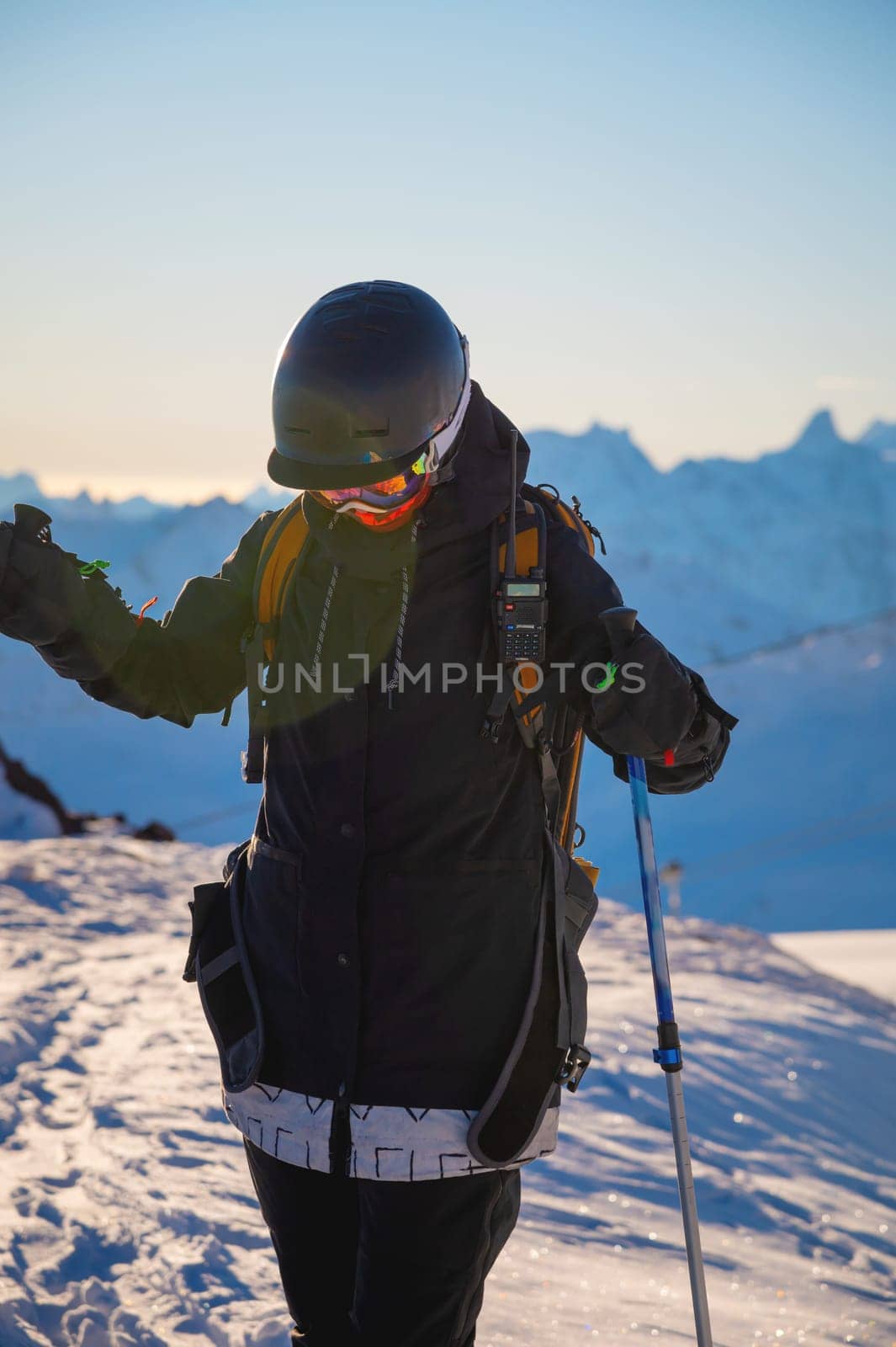 adult girl on skis stands on a mountainside, admiring the mountain landscape, looking at the camera and enjoying the sunny winter weather. Interesting winter activity. side view by yanik88