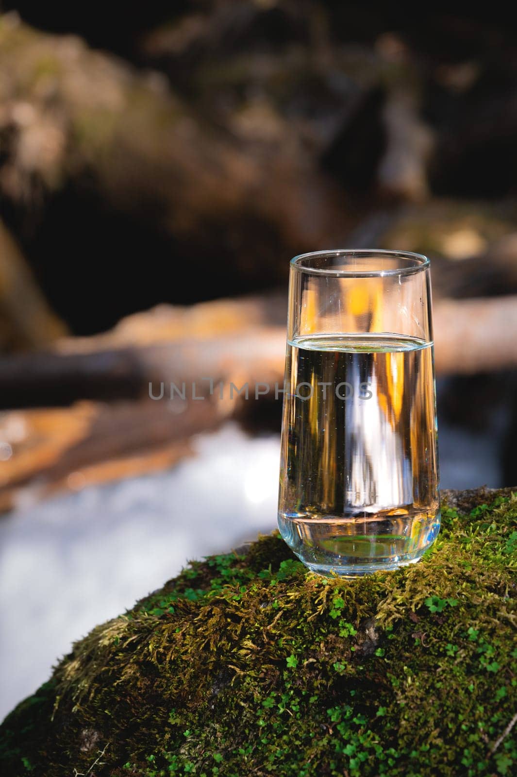 Clean water, healthy concept. Natural drinking water in a glass glass stands on a stone against the backdrop of a river, nature by yanik88