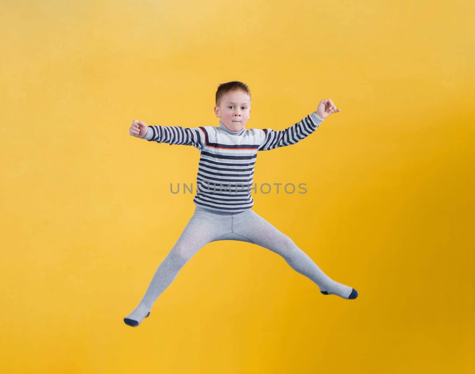 Happy boy jumping on yellow background by Mariakray