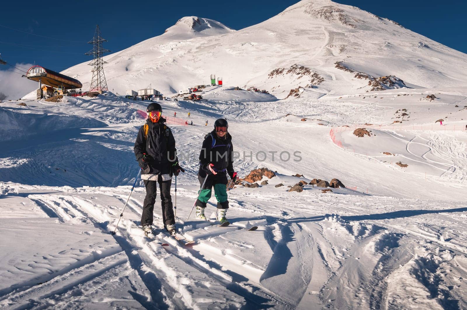 pair of skiers standing on skis side by side in a helmet and goggles getting ready for the descent. The concept of winter friendly outdoor recreation in the mountains by yanik88