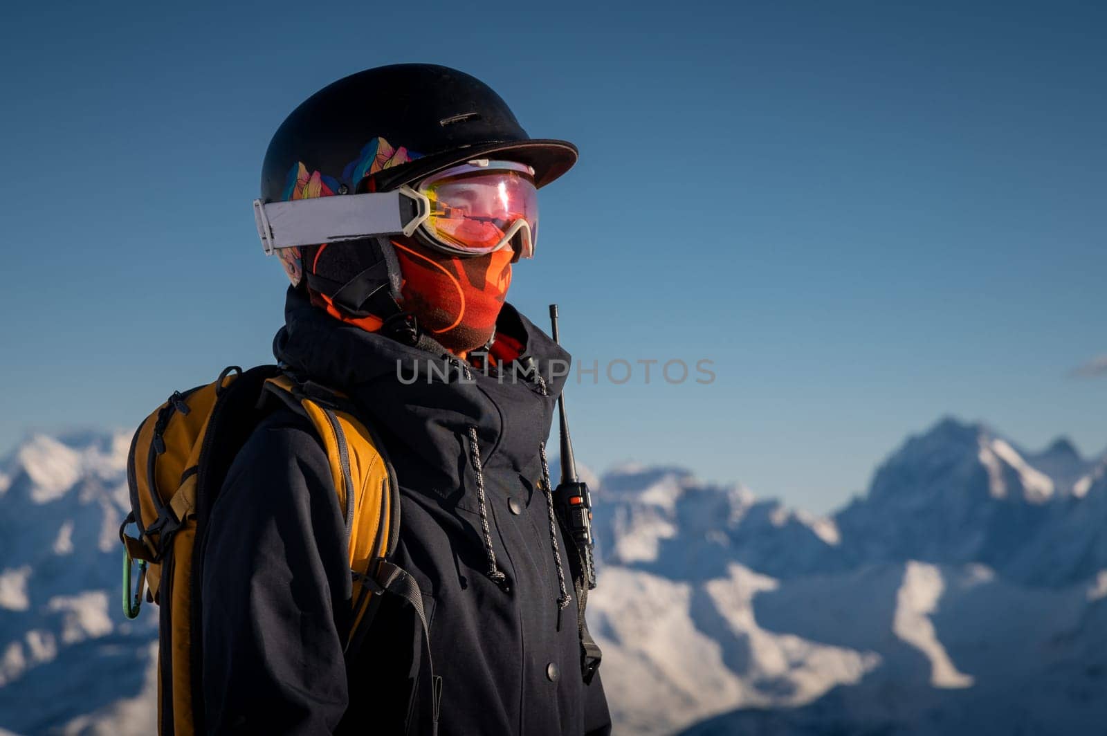 Profile of a female skier in ski goggles in the mountains. A woman in a sports ski jacket and snowboard sunglasses looks away. Sportswear and fashion for winter sports, ski resort by yanik88