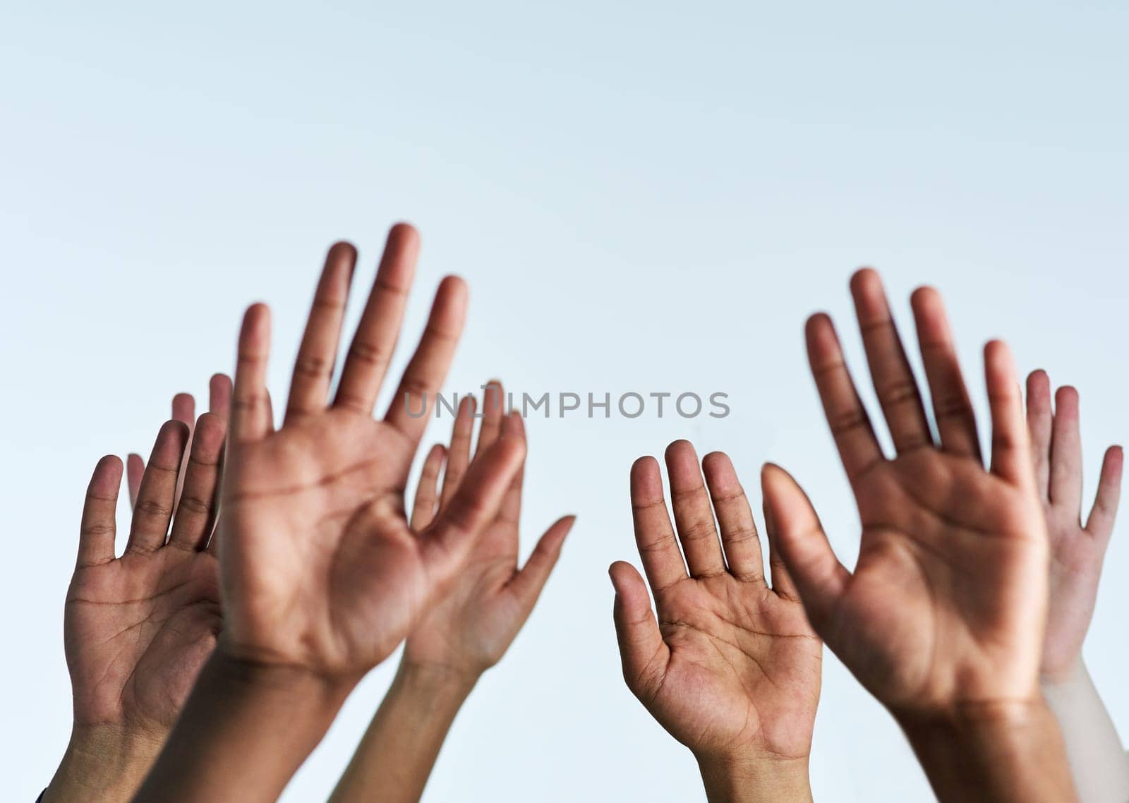 Shot of a group of hands reaching up against a white background.