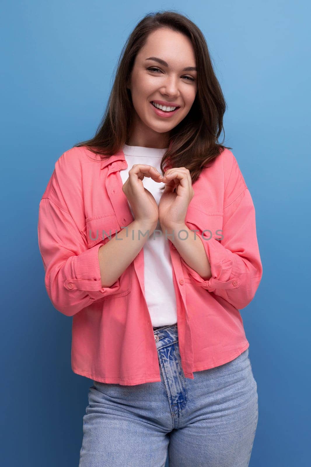 portrait of optimistic brunette young woman in shirt and jeans in studio.