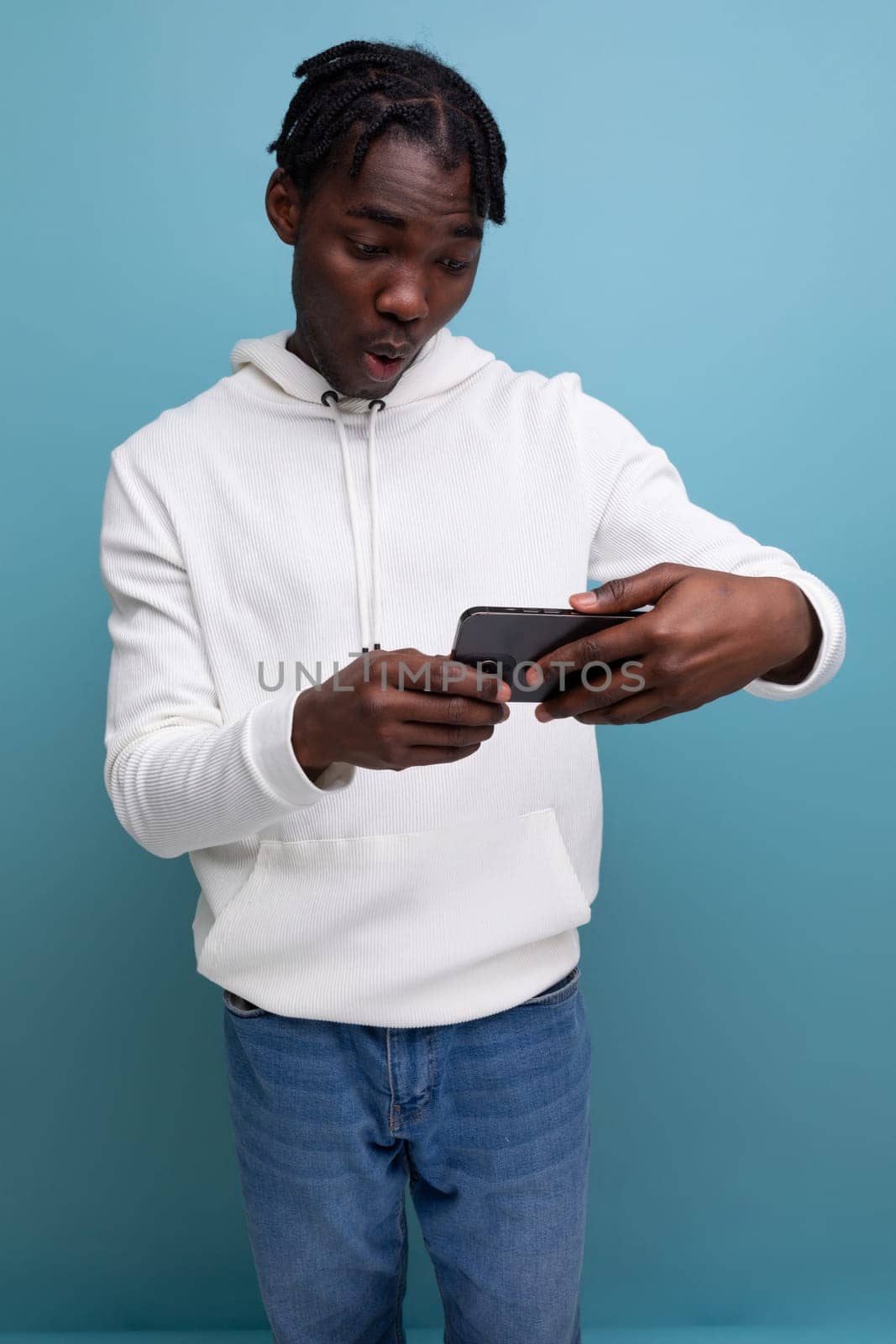 young american guy in white sweatshirt watching video on mobile phone.