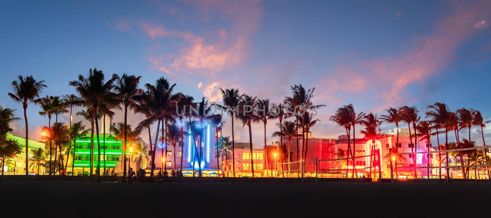 Miami Beach Ocean Drive panorama with hotels and restaurants at sunset. City skyline with palm trees at night by Mariakray