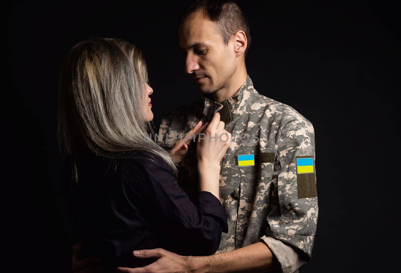 Soldier in military uniform reunited with his family and Ukrainian flag.