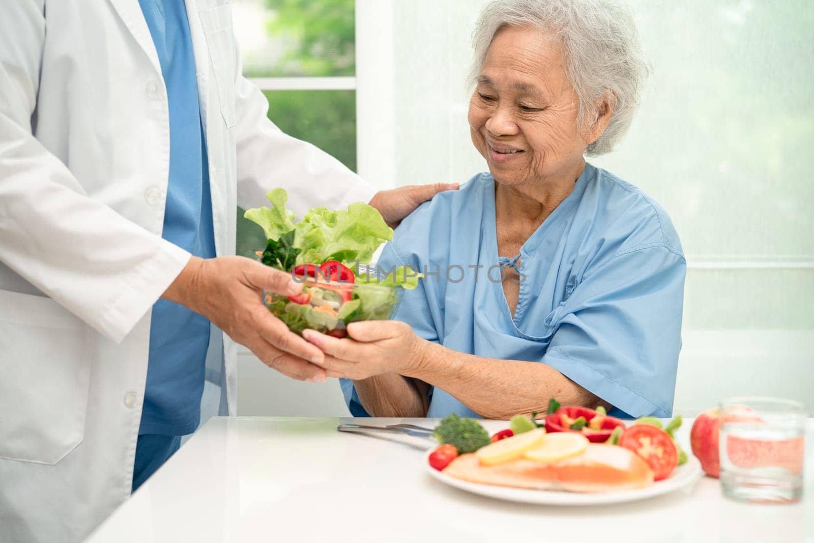 Asian elderly woman patient eating salmon steak breakfast with vegetable healthy food in hospital. by pamai