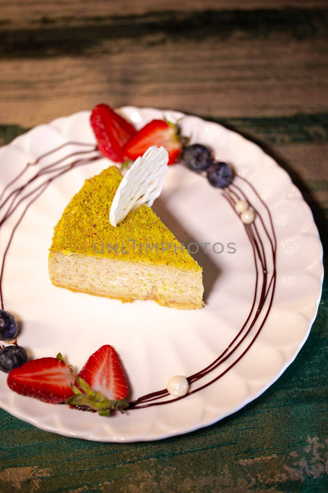 pistachio cheesecake with berries on a plate in a restaurant by Pukhovskiy