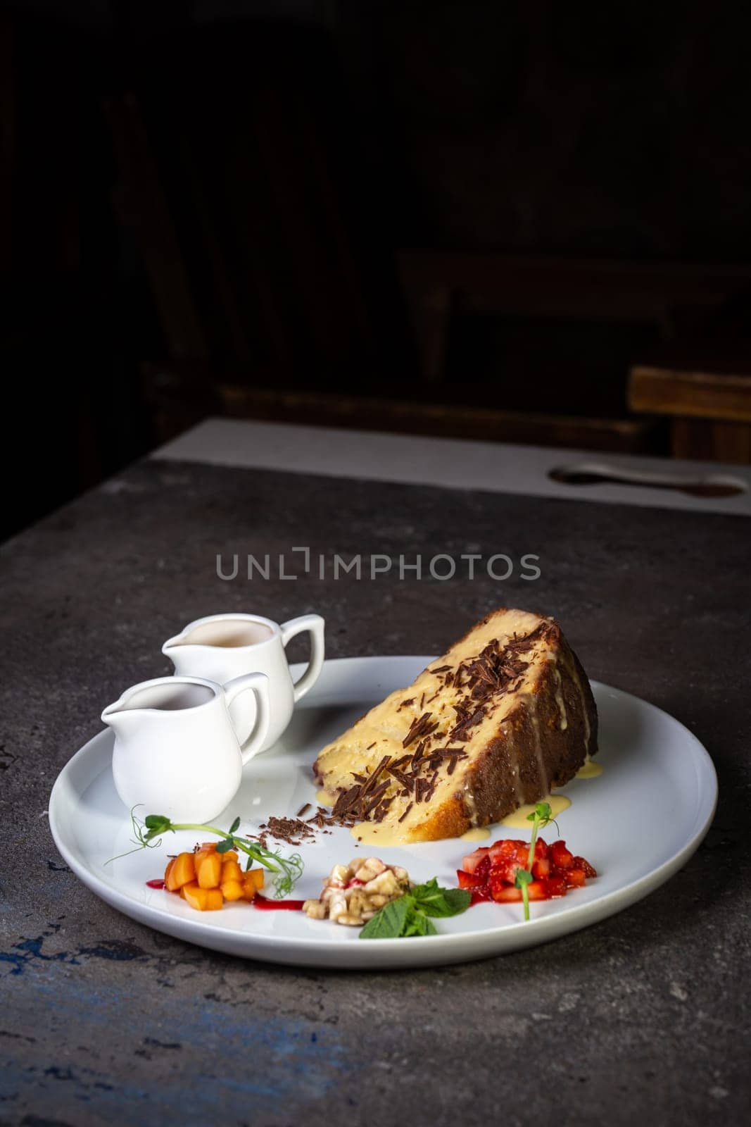 sponge dessert with chocolate chips and fruit on a white plate.