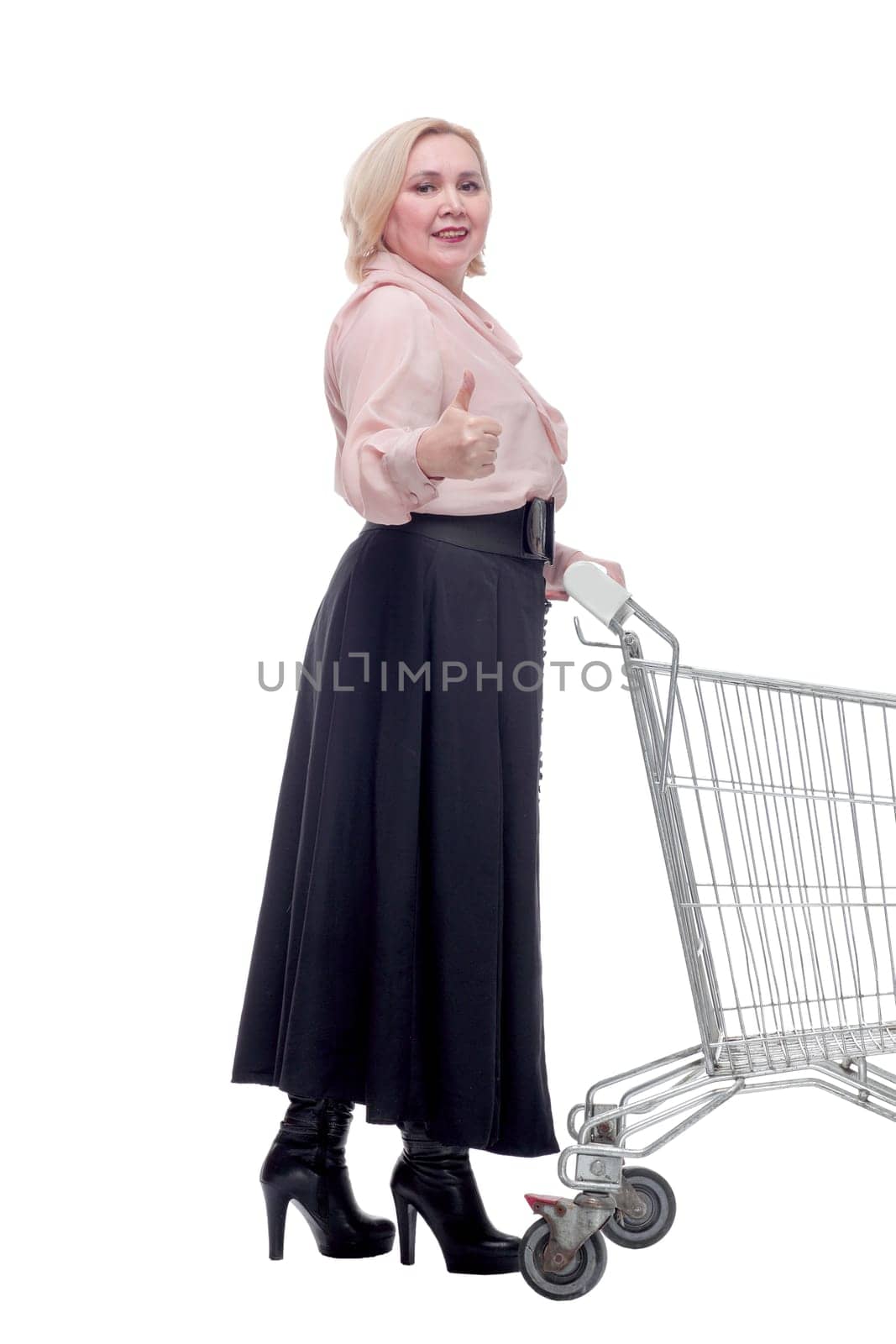Happy blonde woman with shopping cart trolley in sale season. Shopaholic concept.