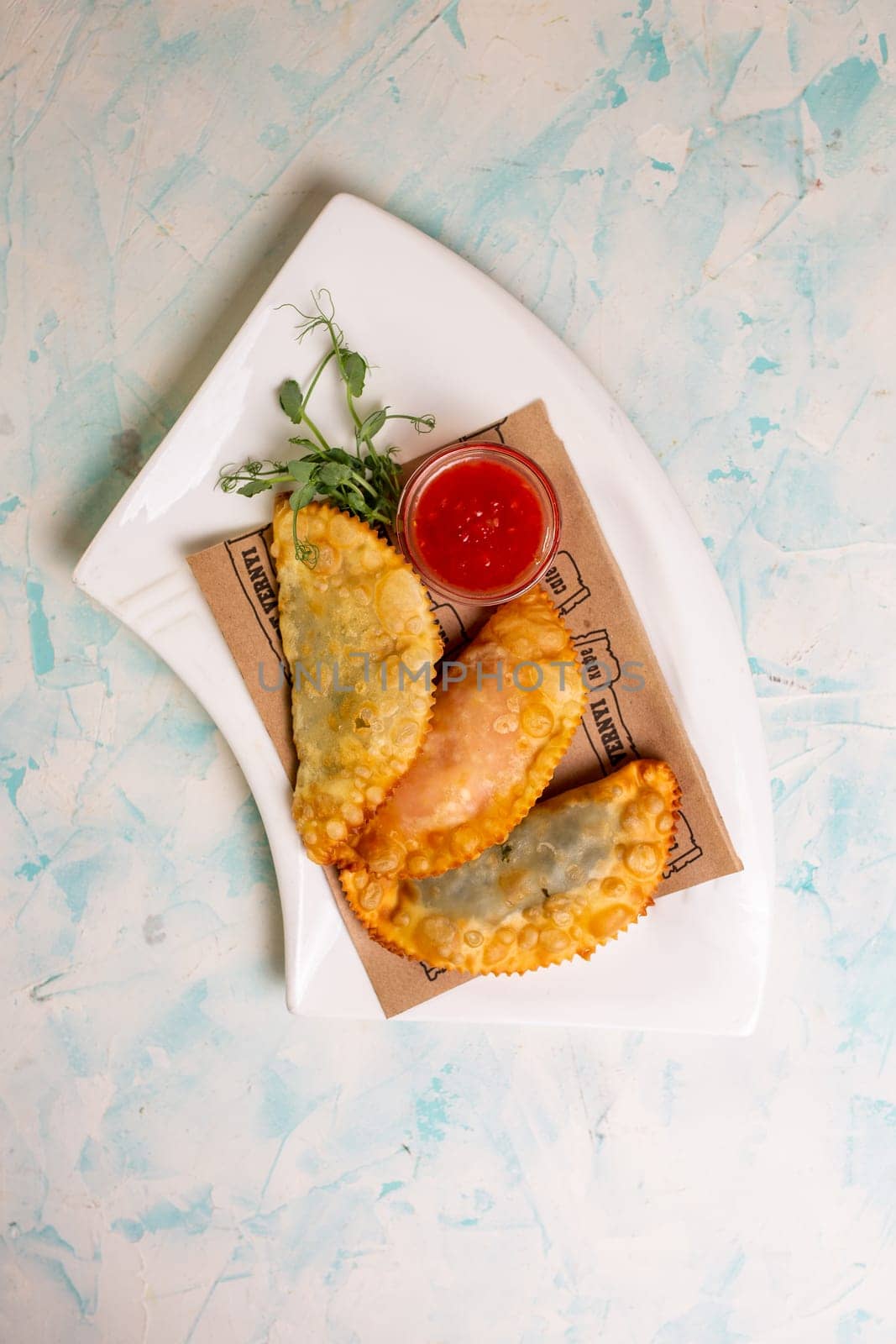 top view of delicious pasties with sauce on a white plate.