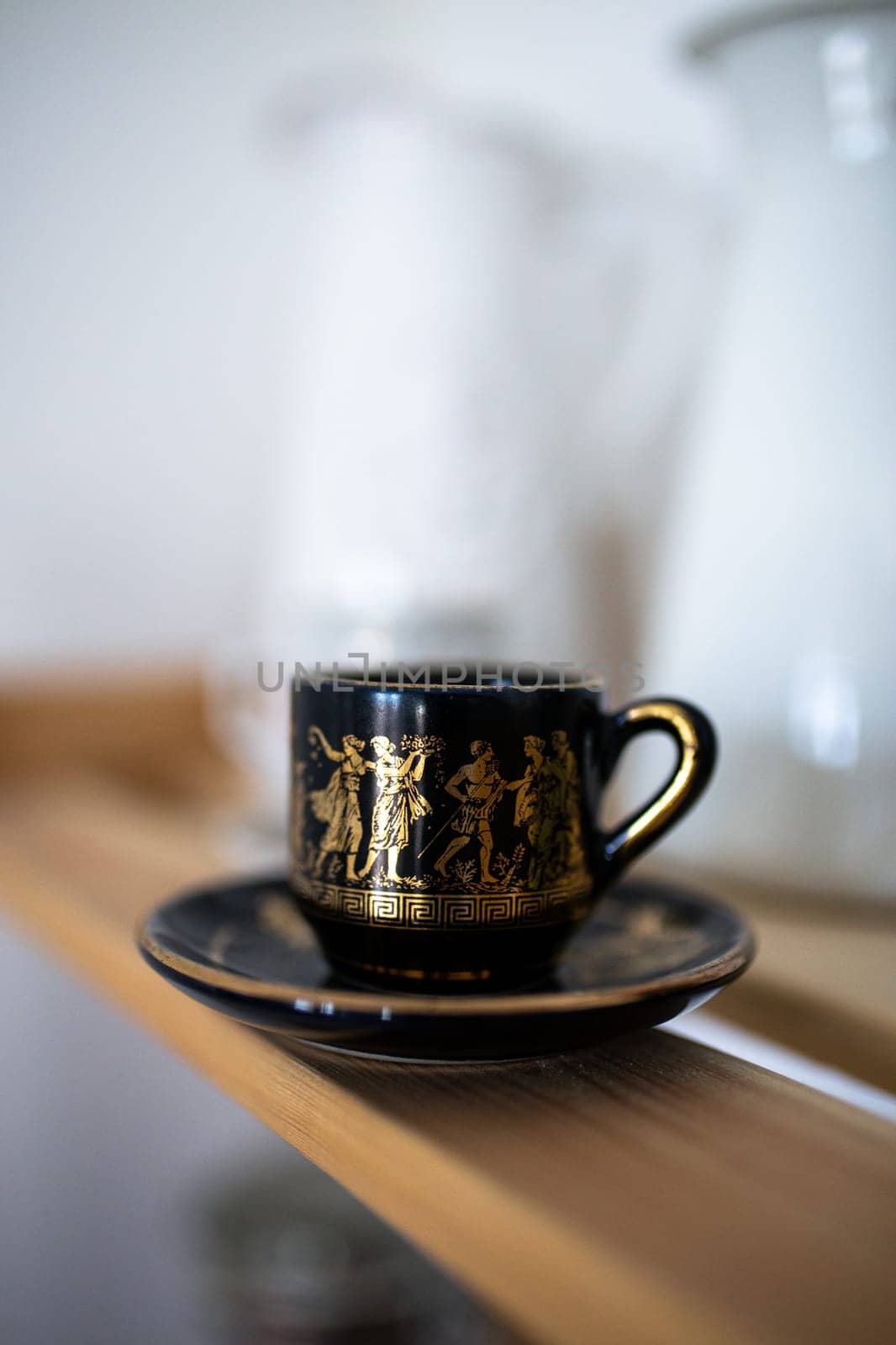 black mug with patterns and print of ancient Greek mythology.