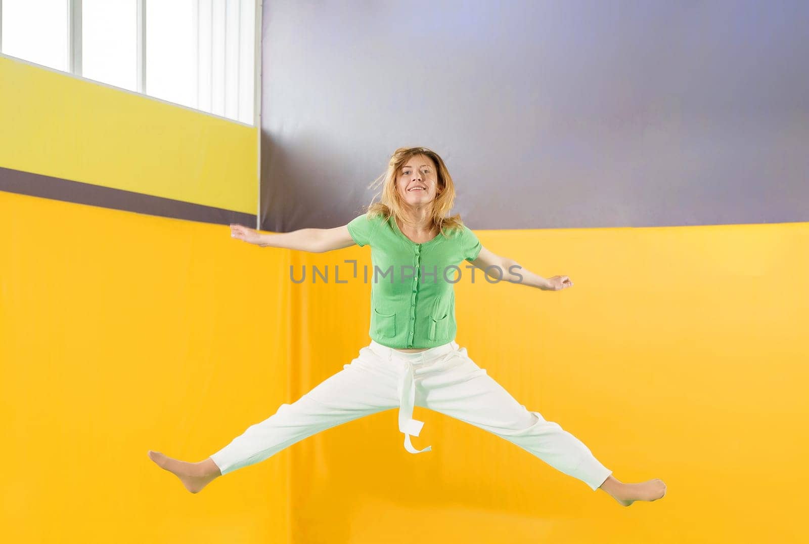 Young girl jumping on a trampoline in sport center by Mariakray