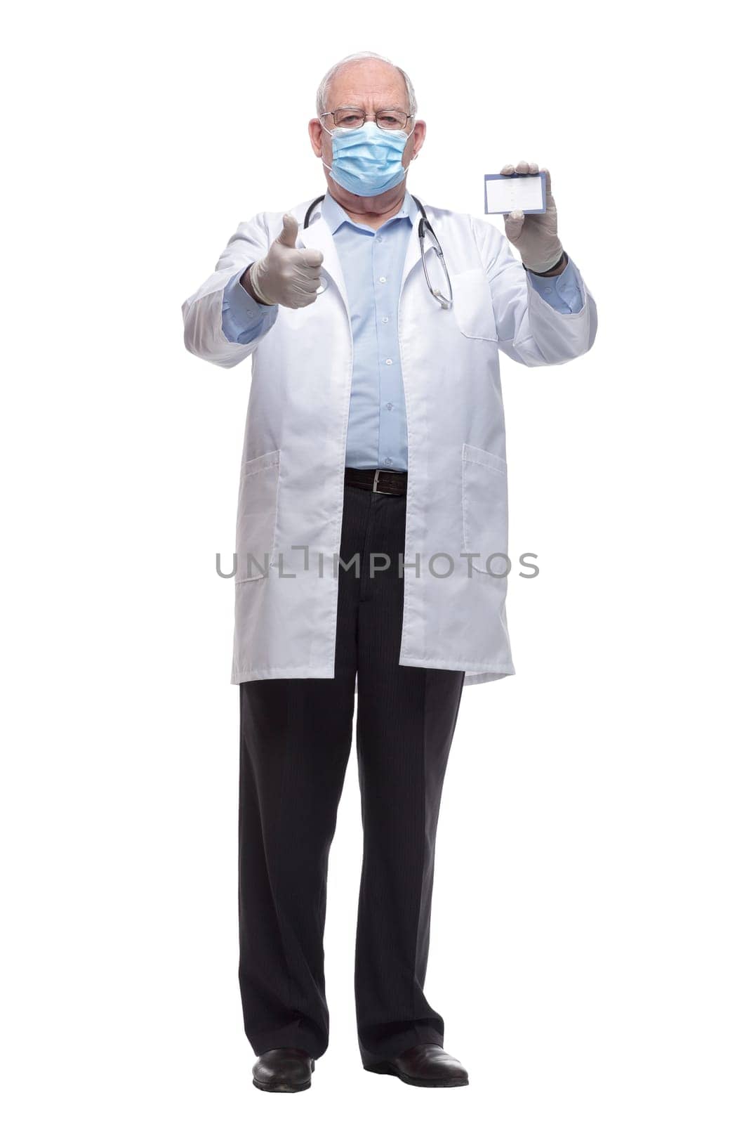 in full growth. doctor in protective mask showing his visiting card. isolated on a white background